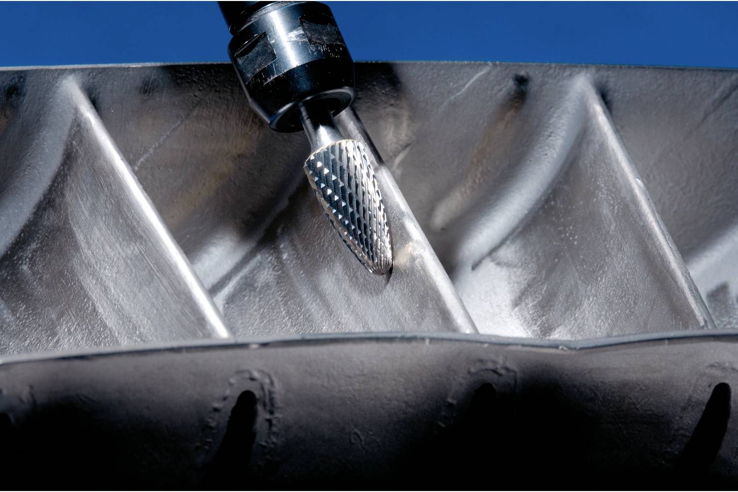 Eine Fräsmaschine bearbeitet eine metallische Oberfläche mit einem kegelförmigen Werkzeug, das für präzise Schneidearbeiten verwendet wird.