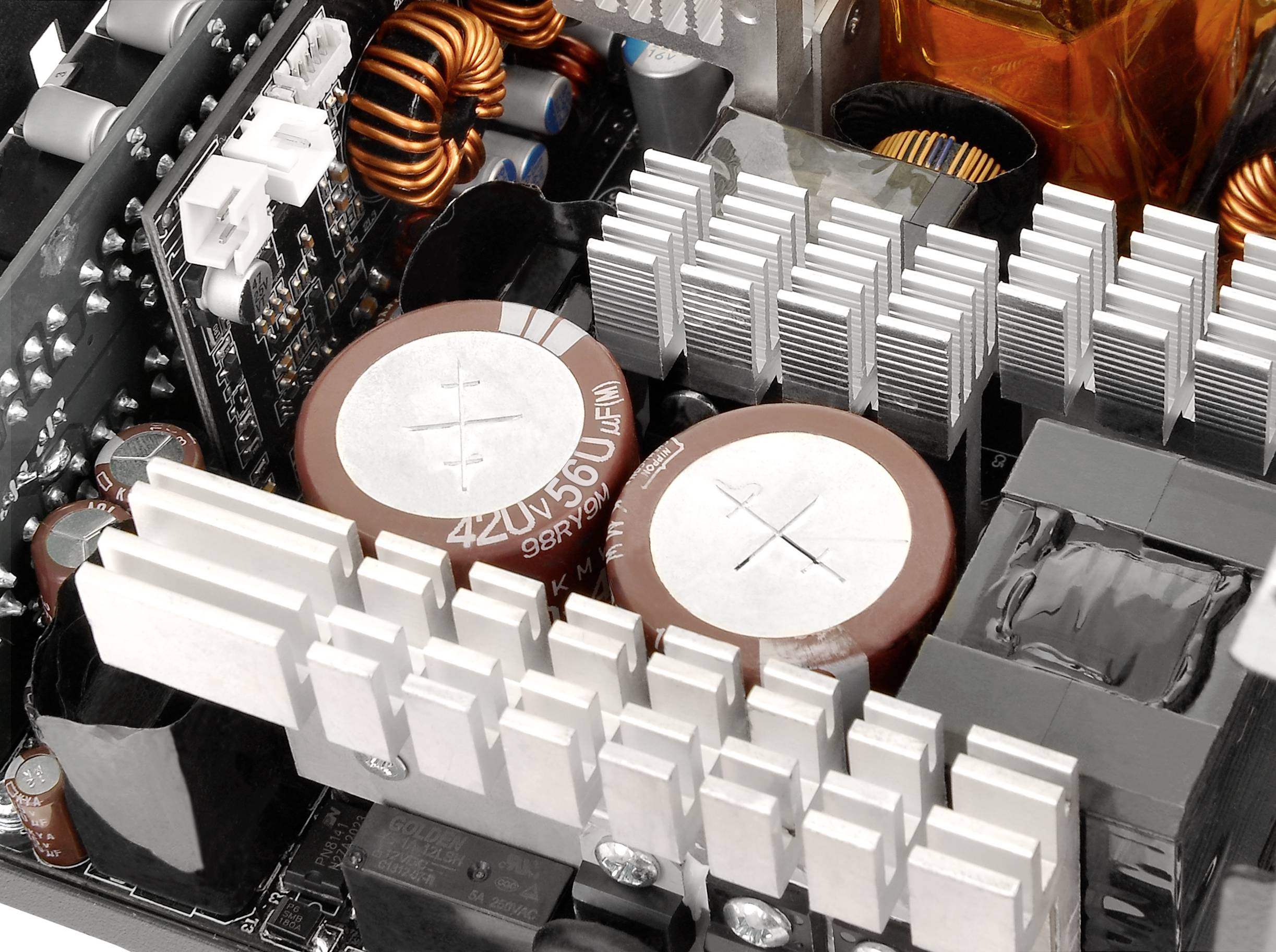 Leiterplatte mit elektronischen Komponenten wie Kondensatoren, Kühlkörpern und Spulen, typisch für einen Computerstromversorgung.