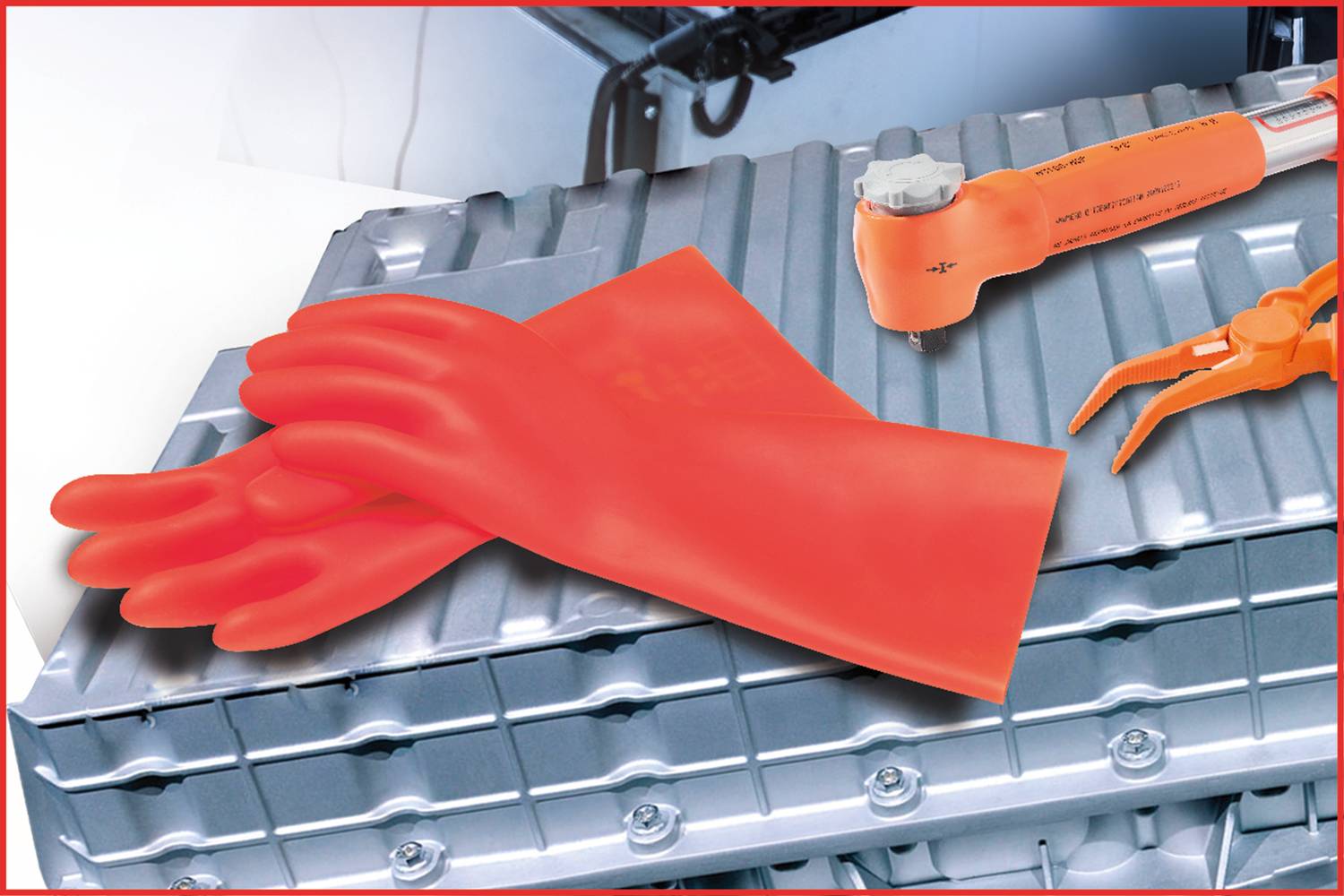 Rote Isolierhandschuhe und Werkzeuge liegen auf einem silberfarbenen Metallgehäuse, das möglicherweise einen technischen Aufbau darstellt.