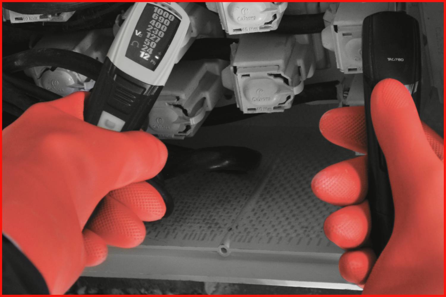Eine Person mit roten Handschuhen überprüft elektrische Verbindungen mit einem Spannungsmesser in einem Schaltschrank.
