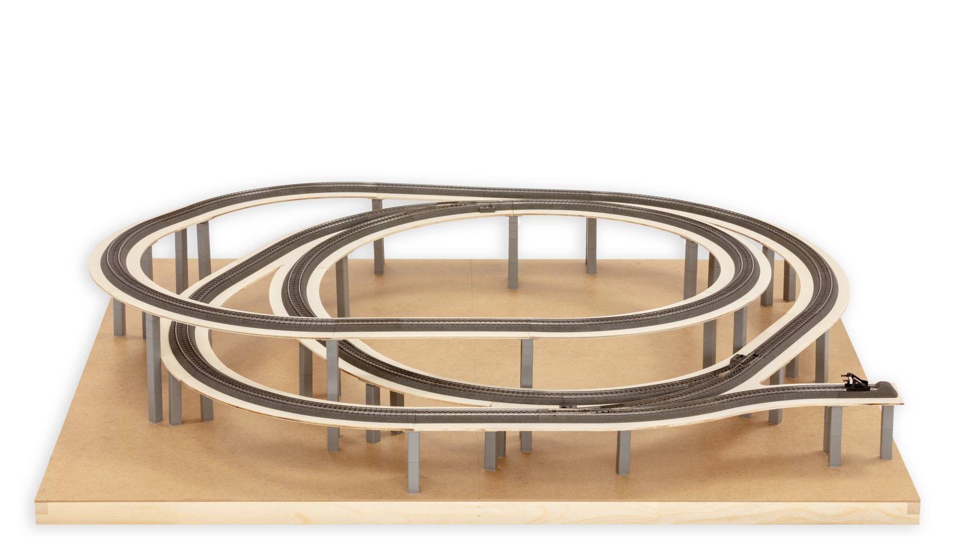 Eine komplexe Modellbahnanlage mit mehrspurigen, auf mehreren Ebenen verlaufenden Gleisen, aufgebaut auf einer rechteckigen Holzplatte.
