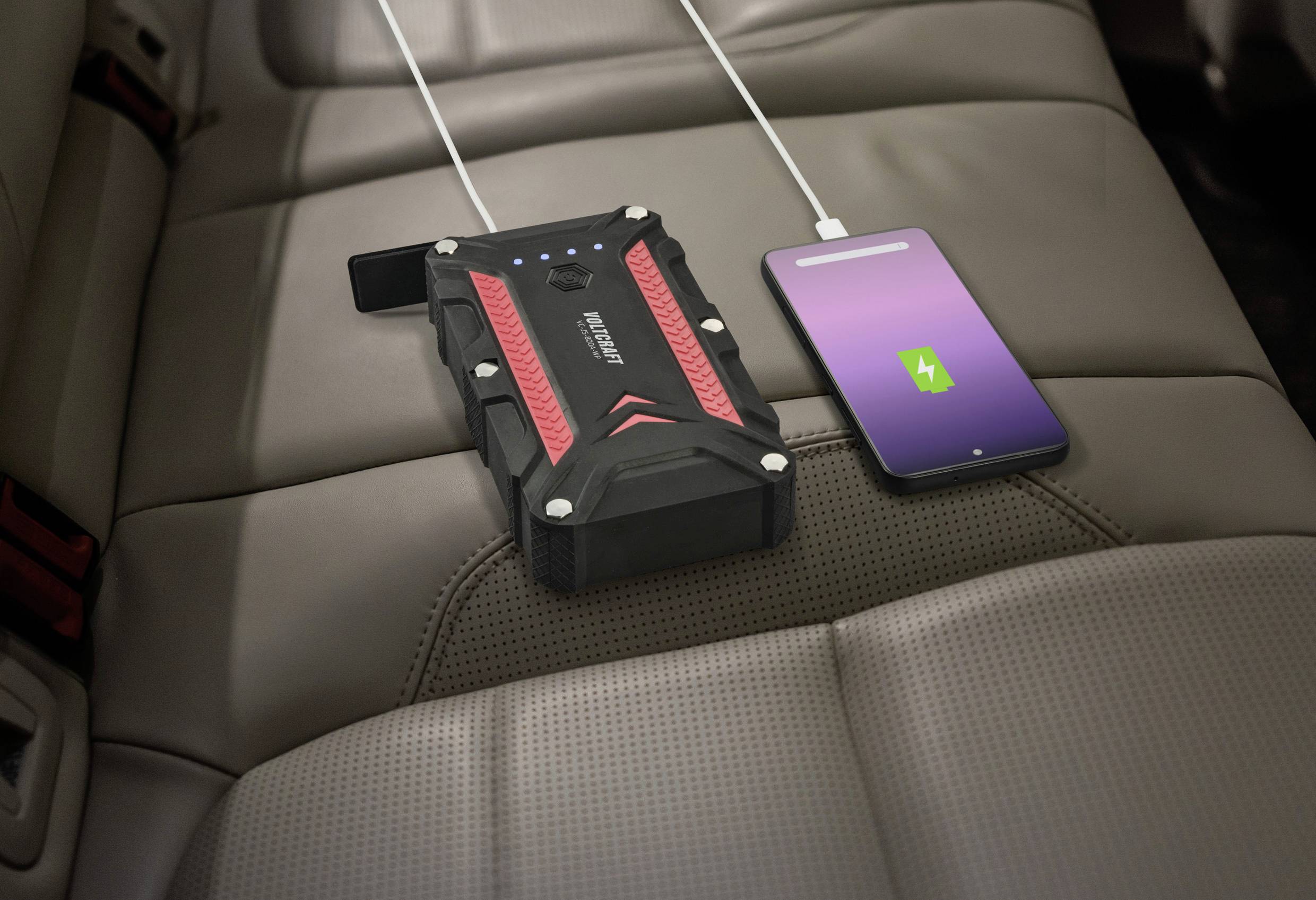 Externe Powerbank auf Autositz lädt ein Smartphone.