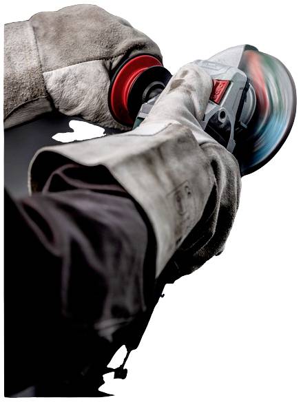 Eine Person trägt Arbeitshandschuhe und benutzt einen Winkelschleifer, um Metall zu schleifen. Funken fliegen von der Schleifscheibe.