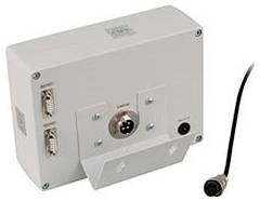 Eine an der Wand montierte elektronische Schaltkiste mit zwei seitlichen Anschlüssen, einer zentralen kreisförmigen Öffnung und einem nach rechts führenden Kabel.