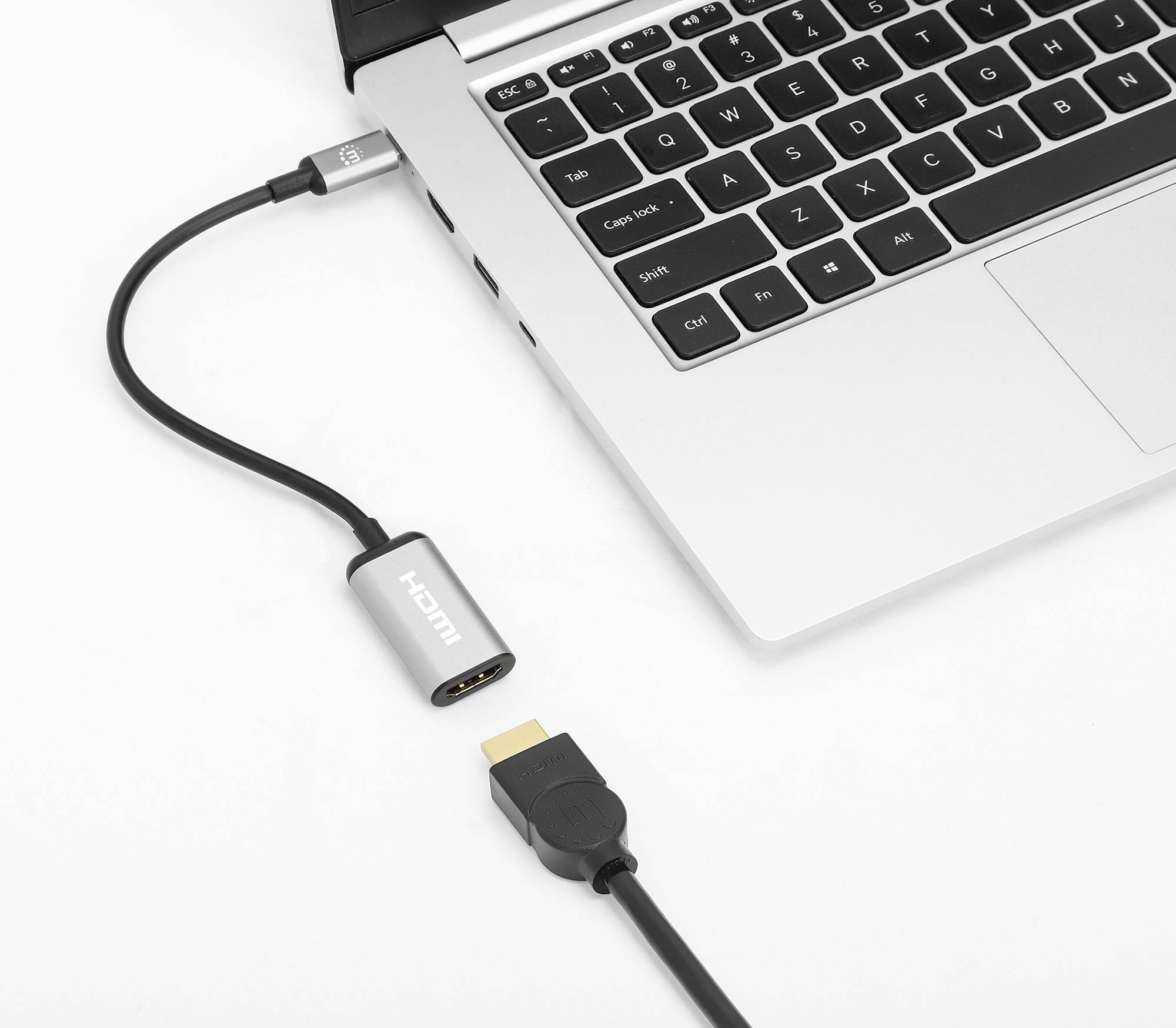 Ein HDMI-Kabel wird über einen Adapter an einen Laptop angeschlossen. Der Laptop ist teilweise sichtbar und zeigt die Tastatur.