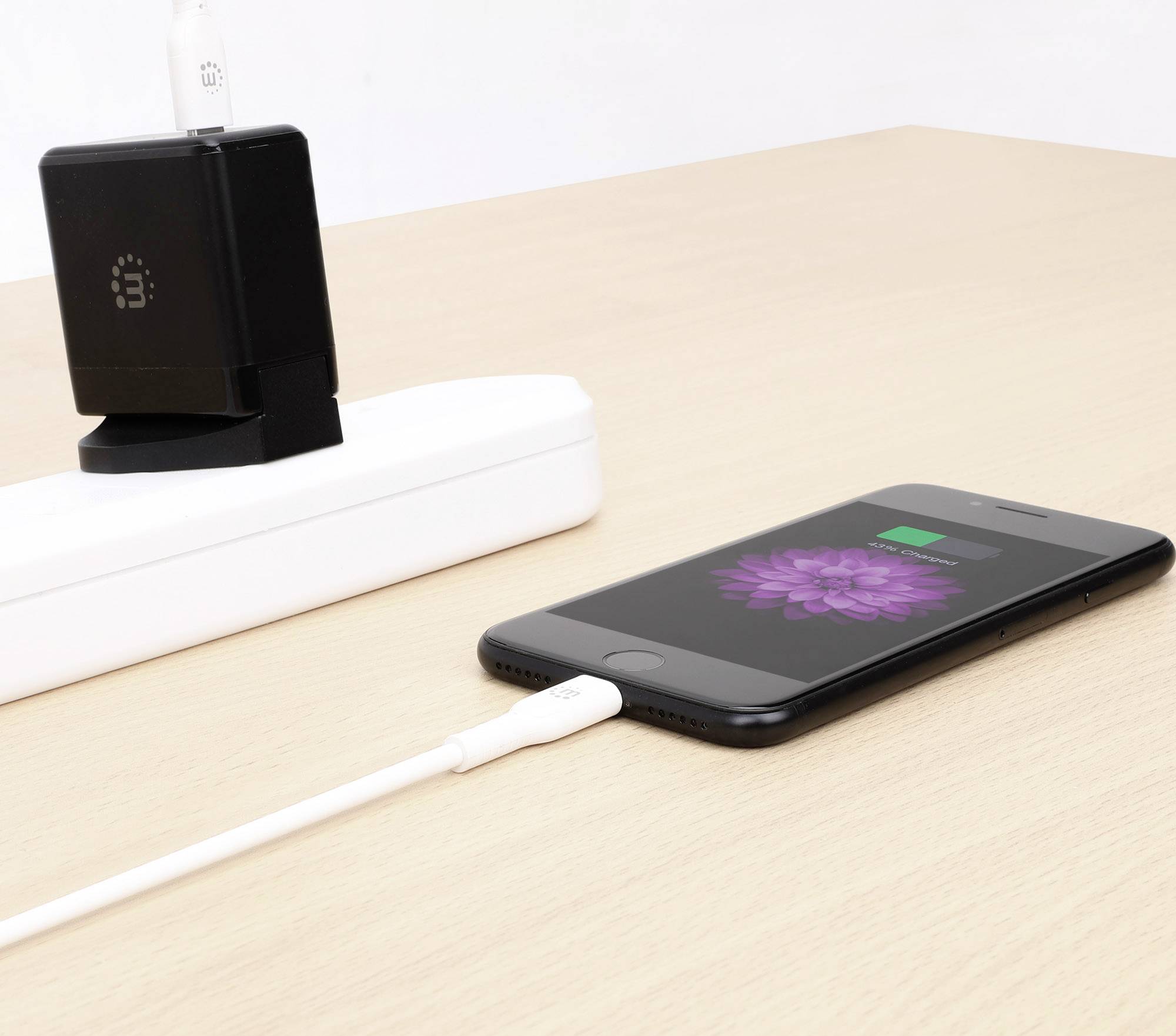 Smartphone lädt auf Tisch mit USB-Kabel, angeschlossen an eine Steckdosenleiste. Ladeanzeige auf Bildschirm sichtbar.