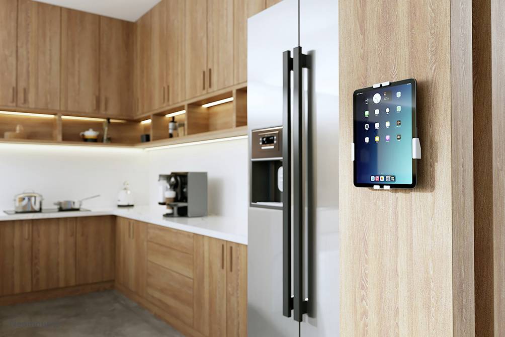 Moderne Küche mit Holzschränken, großem Edelstahlkühlschrank und Tablet an der Wand. Helle Beleuchtung betont minimalistisches Design.