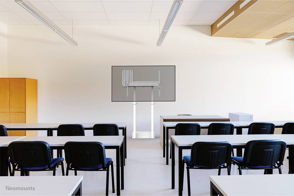 Klassenzimmer mit Reihen von Tischen und Stühlen, ein großer Bildschirm vorne, Lehrerbereich auf der rechten Seite.