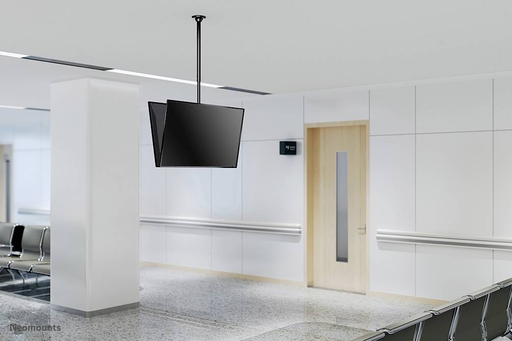 Ein leerer Warteraum mit Stühlen entlang der Wand, einem hängenden Fernseher und einer geschlossenen Holztür.