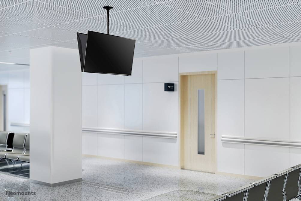 Leerer Warteraum mit weißen Wänden, Linoleum-Boden, schwarzen Stühlen entlang der Wand und einem Flachbildschirm an der Decke.