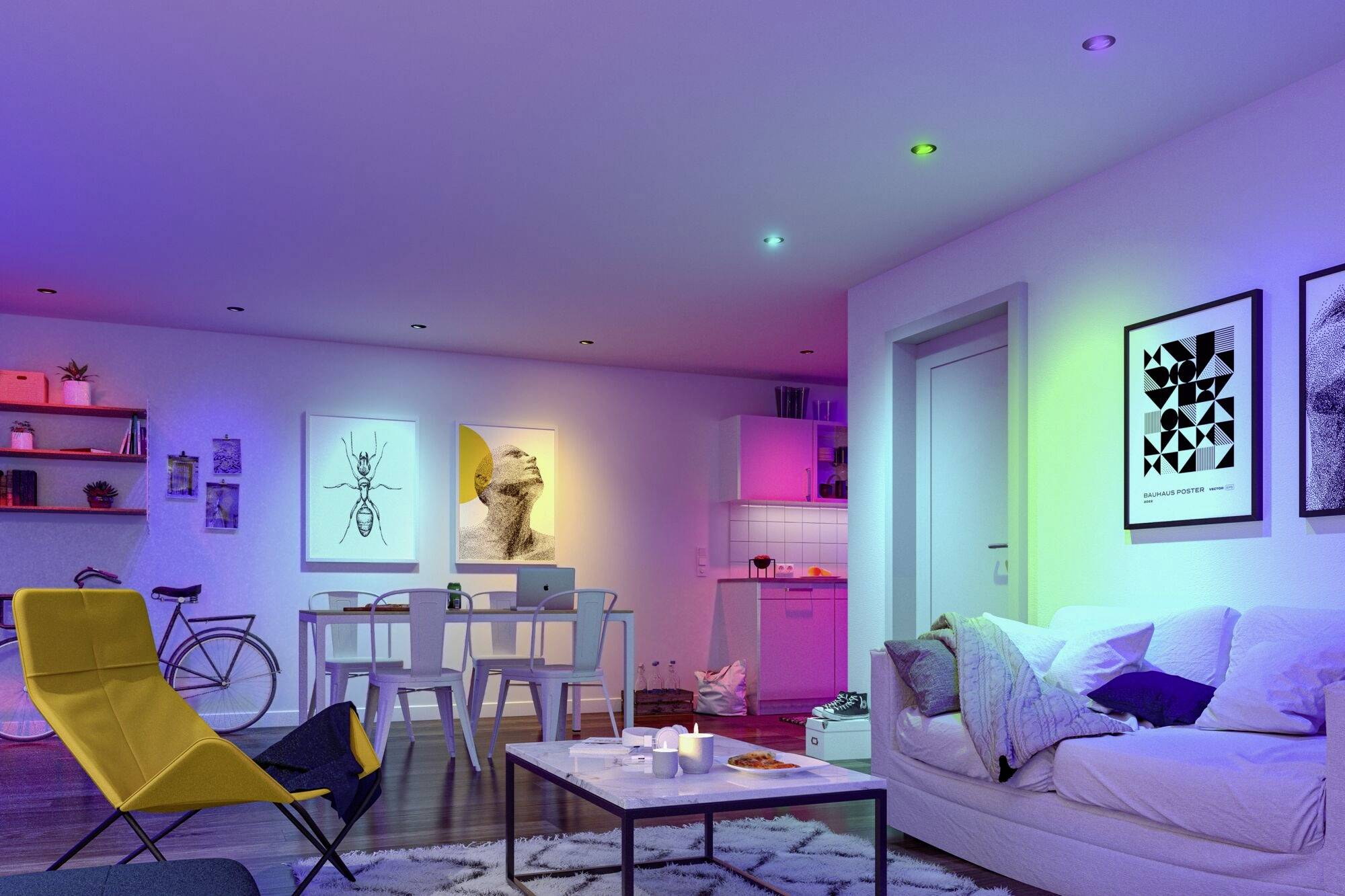 Wohnzimmer mit Sofa, Tisch und farbiger Beleuchtung. Dekorative Bilder an der Wand, Fahrrad an der Ecke und offene Küche im Hintergrund.