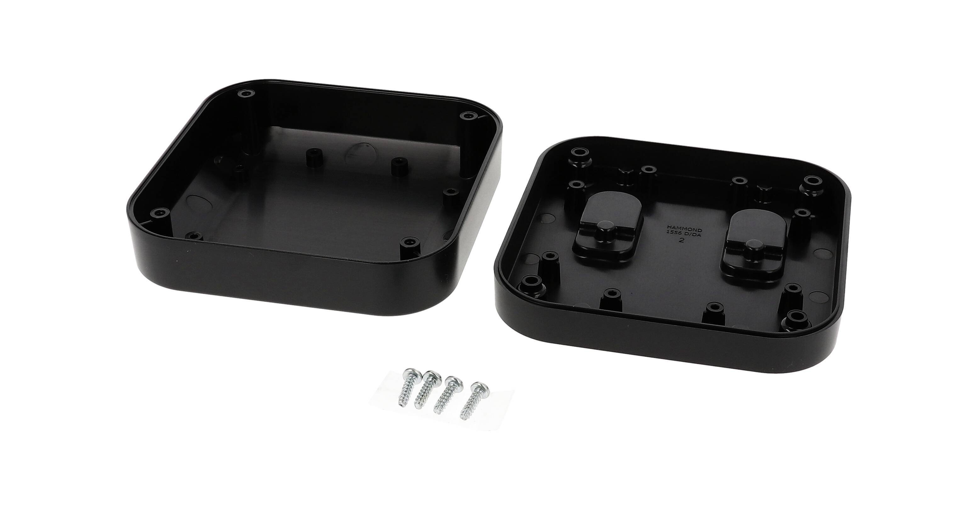 Schwarzes rechteckiges Gehäuse, offen präsentiert. Innen Schraubplätze sichtbar. Fünf silberne Schrauben liegen davor.