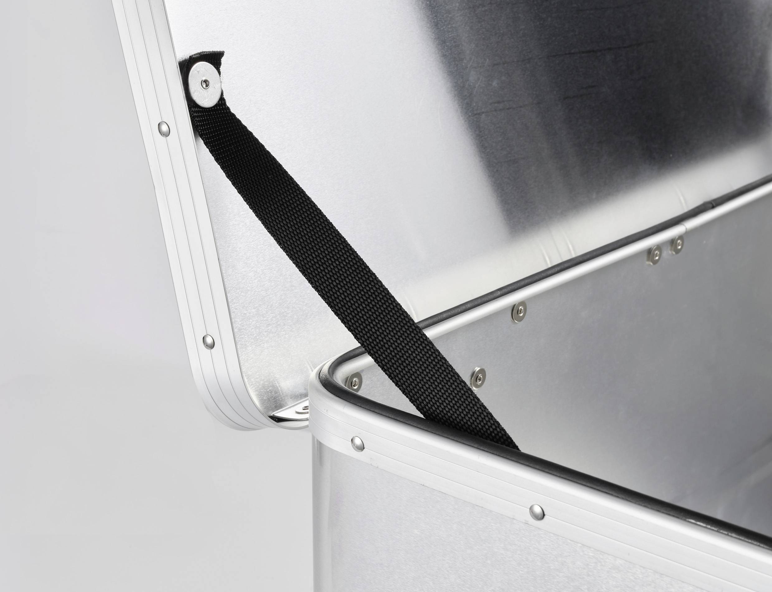 Ein geöffneter Aluminiumkoffer mit einem schwarzen Riemen, der den Deckel hält, zeigt stabilen Aufbau und industrielle Nutzung.
