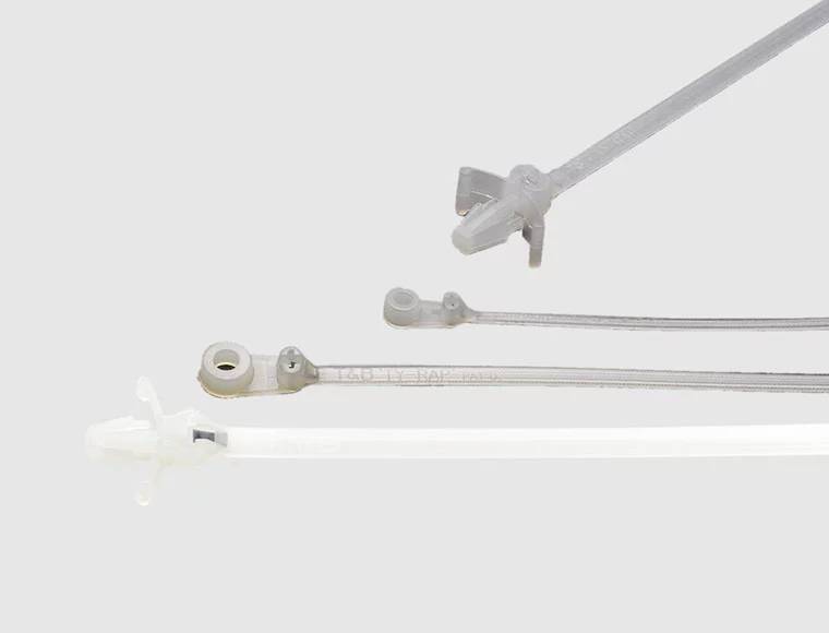 Drei Kabelbinder unterschiedlicher Größe und Farbe auf grauem Hintergrund.