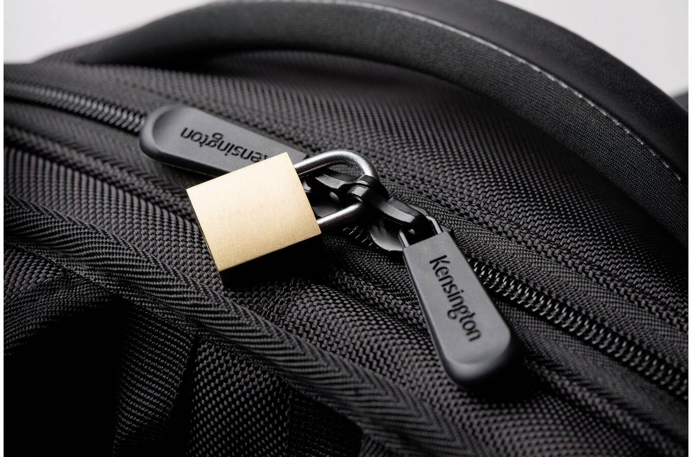 Nahaufnahme eines schwarzen Rucksacks mit einem Vorhängeschloss, das die Reißverschlüsse sichert.