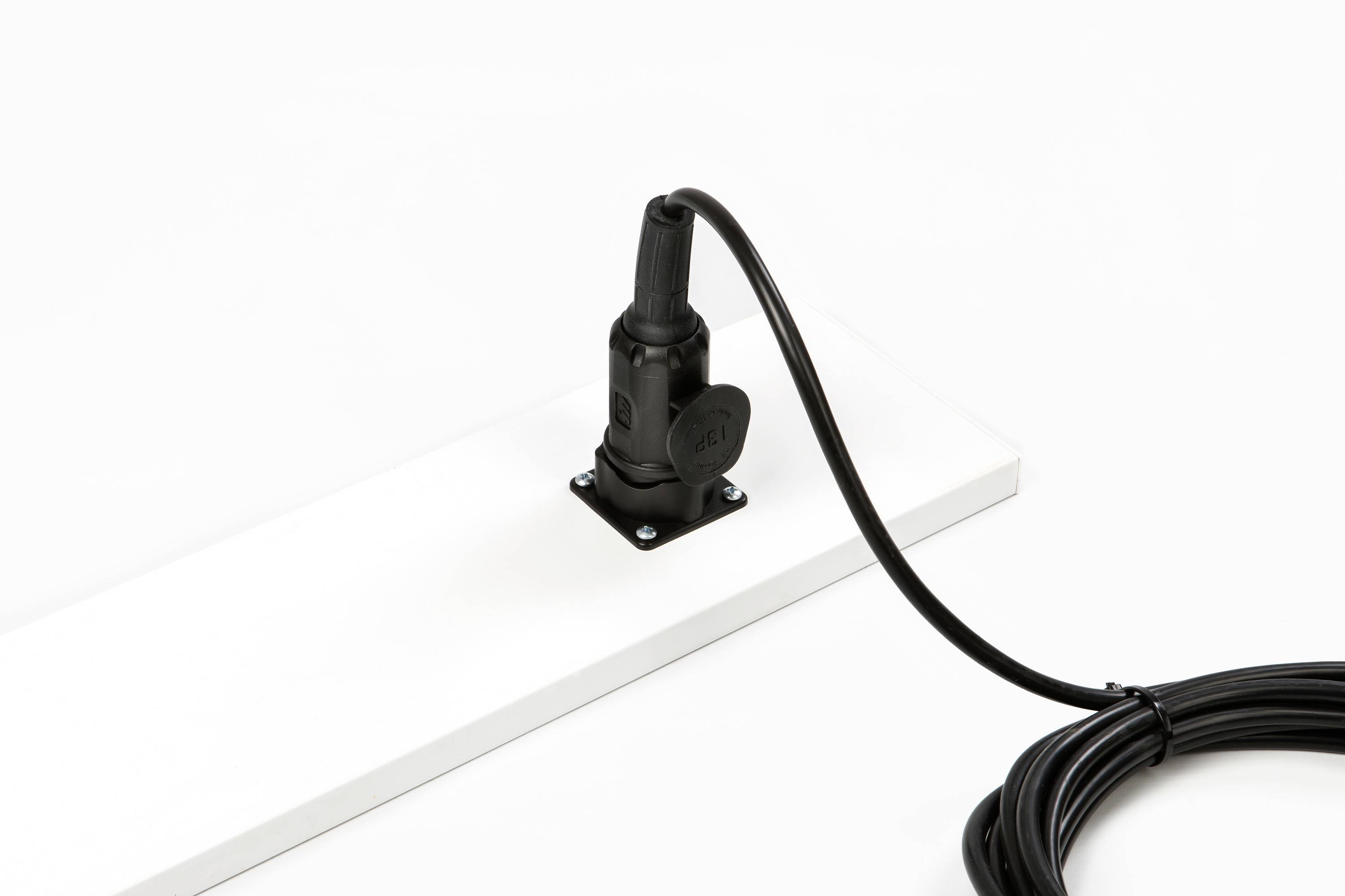 Eine schwarze Kabelrolle ist auf einer weißen Oberfläche platziert, das Kabel ist teilweise abgewickelt.