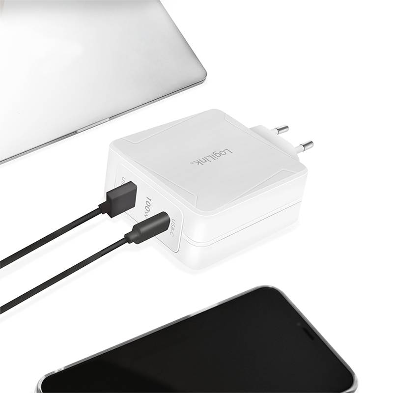 Zwei schwarze USB-Kabel sind an einem weißen Mehrfachladegerät angeschlossen, das neben einem Laptop und einem Smartphone liegt.