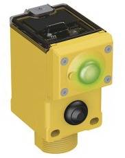 Gelbes elektronisches Gerät mit einem grünen leuchtenden Knopf oben und einem schwarzen Schalter darunter, möglicherweise ein Sensor.