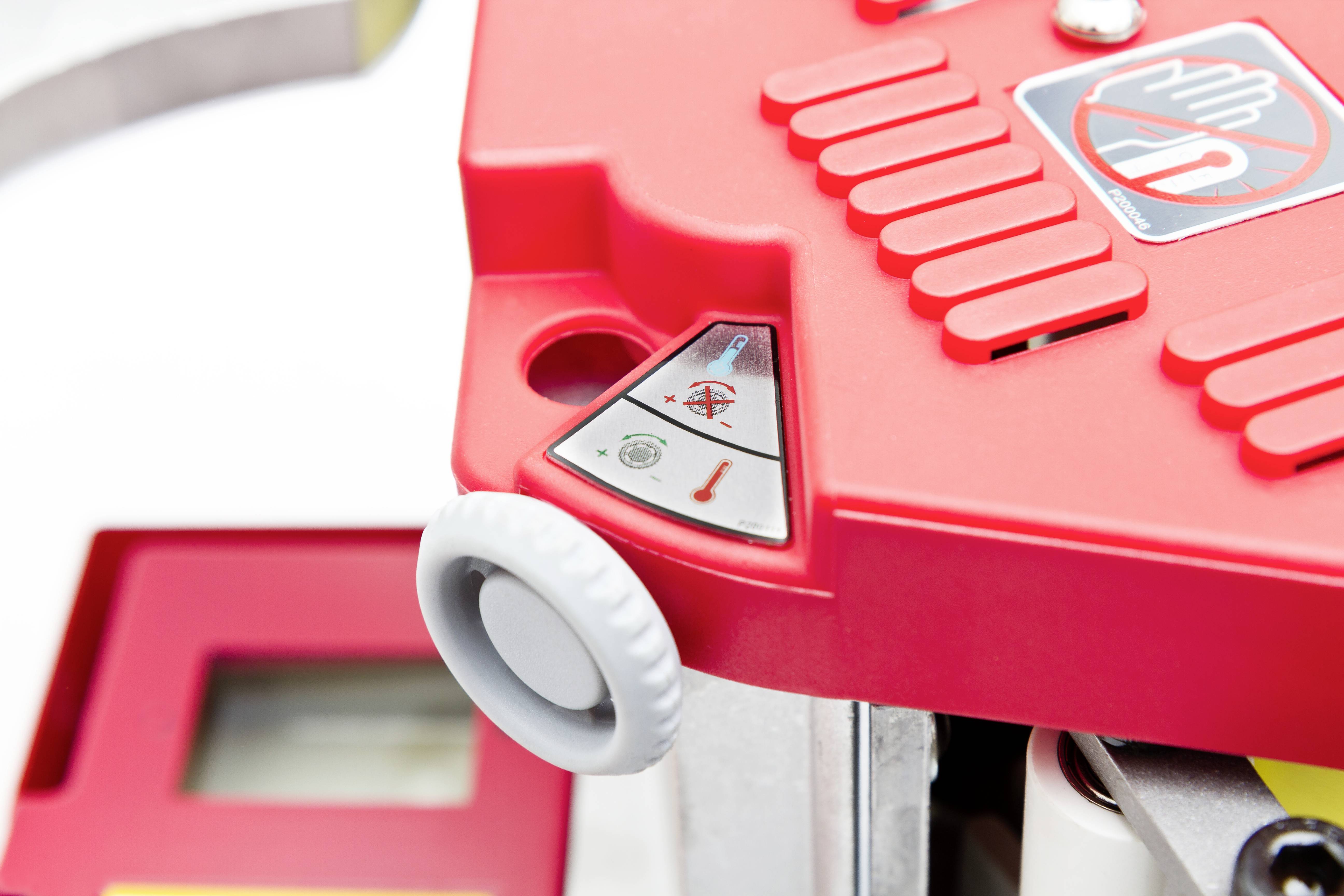 Rote Maschine mit Sicherheitswarnsymbolen und Hebel, zeigt Hinweis auf Gefahr bei Berührung. Hauptmerkmal ist eine weiße Drehknopf.