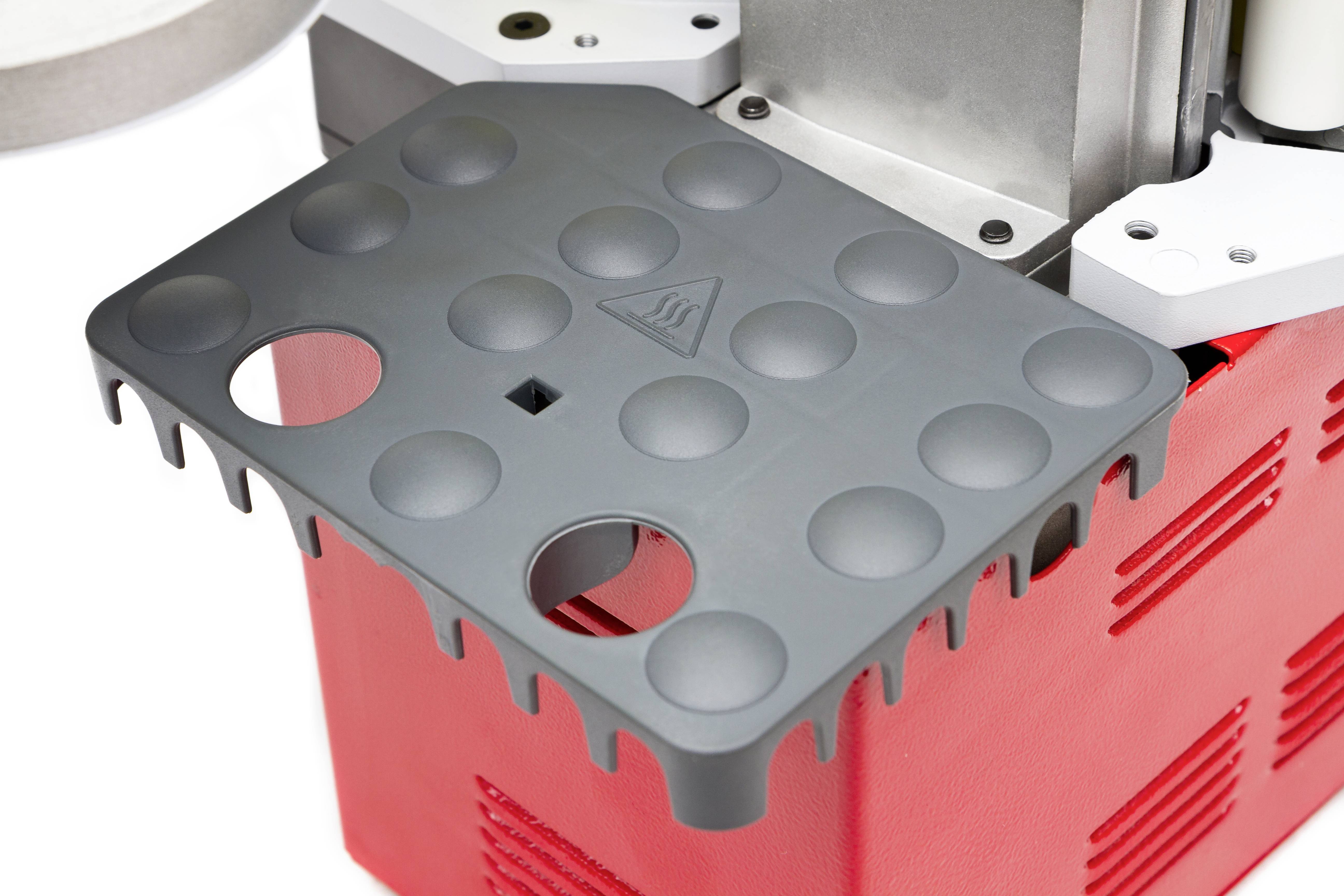 Ein rot-schwarzes technisches Gerät mit einer grauen, gelochten Platte oben drauf.