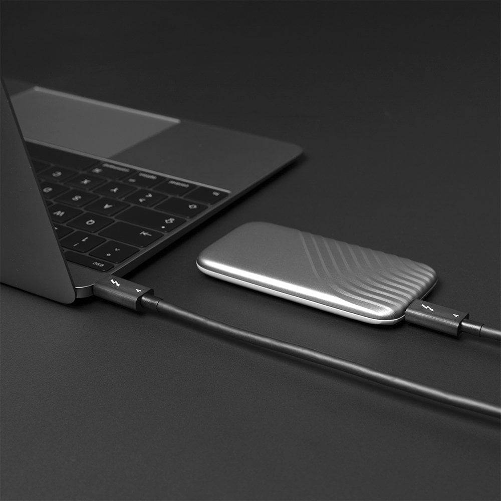 Ein Laptop ist mit einem externen Festplattenlaufwerk über ein Kabel verbunden. Der Hintergrund ist dunkelgrau.