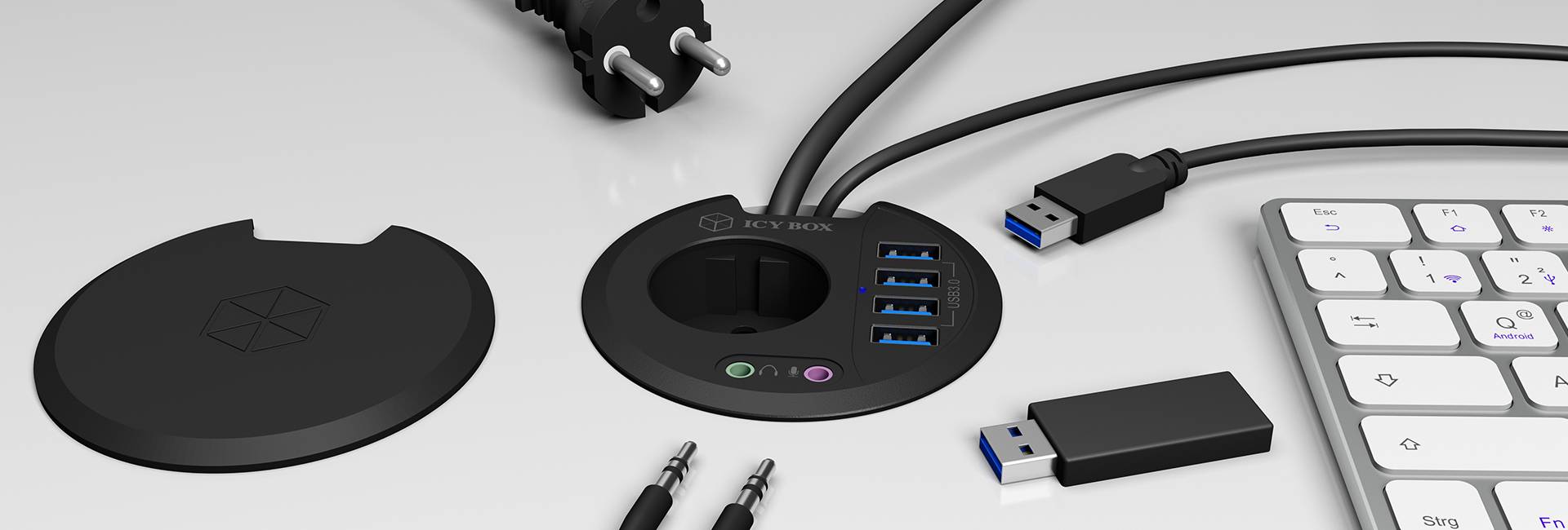 Ein USB-Hub mit vier USB-Anschlüssen, zwei Audiobuchsen, Kabeln und einer Abdeckung liegt neben einer externen Tastatur und einem USB-Stick.