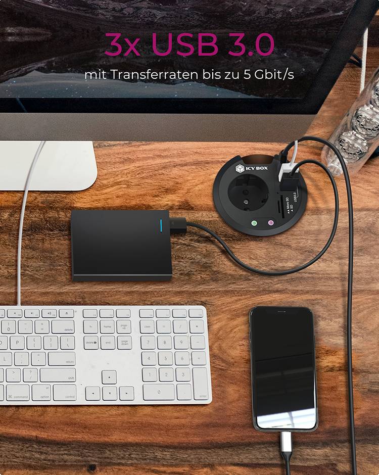 Schreibtischtisch mit Computer, Tastatur, externer Festplatte, Smartphone und Steckdose mit USB-Anschlüssen.