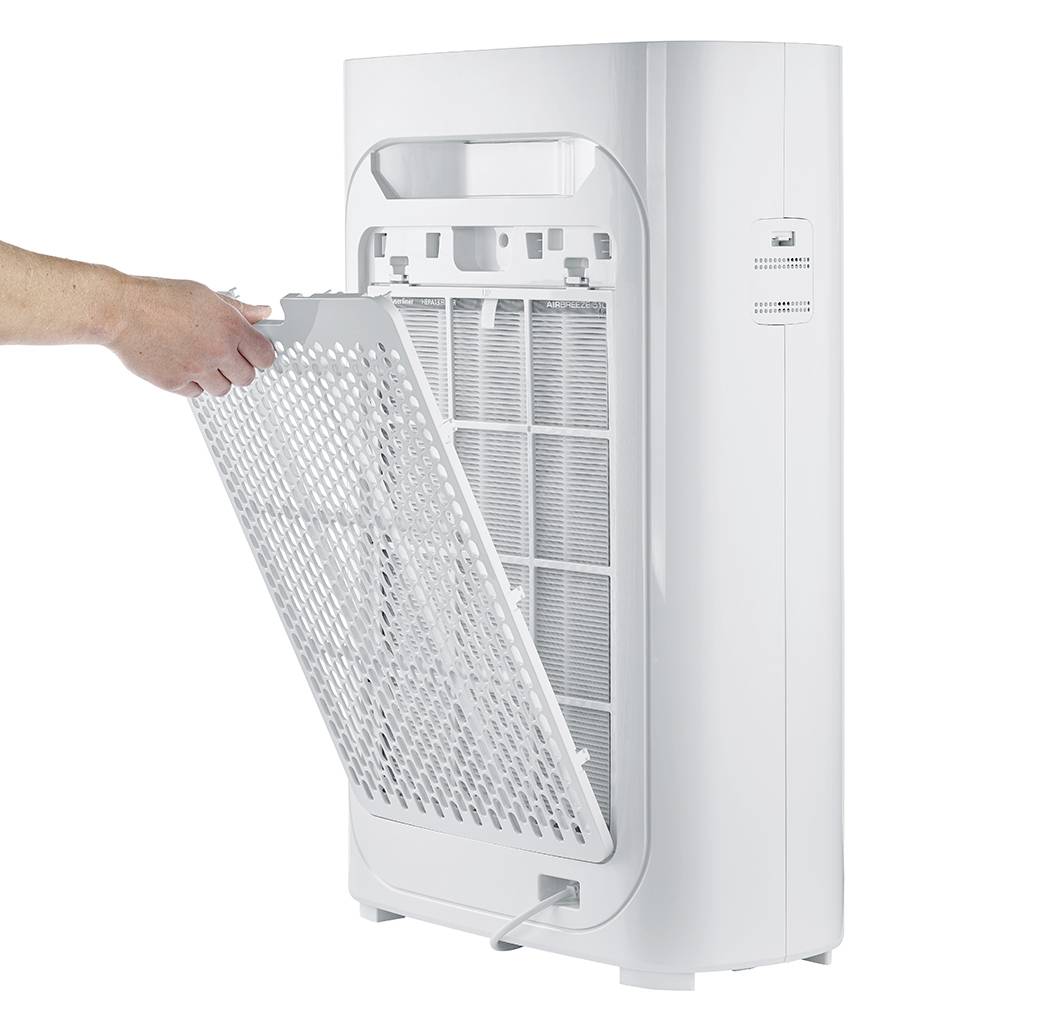 Eine Person entfernt den Filter von einem weißen Luftreiniger. Das Gerät steht aufrecht, während der Filter zur Reinigung entnommen wird.