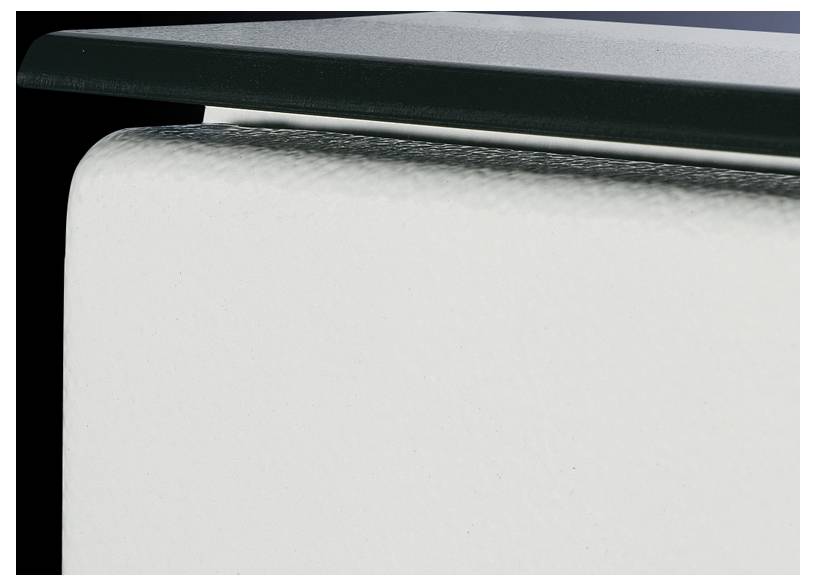 Eine Nahaufnahme eines Teils eines weißen, texturierten Objekts mit einer dunklen Oberkante auf schwarzem Hintergrund.