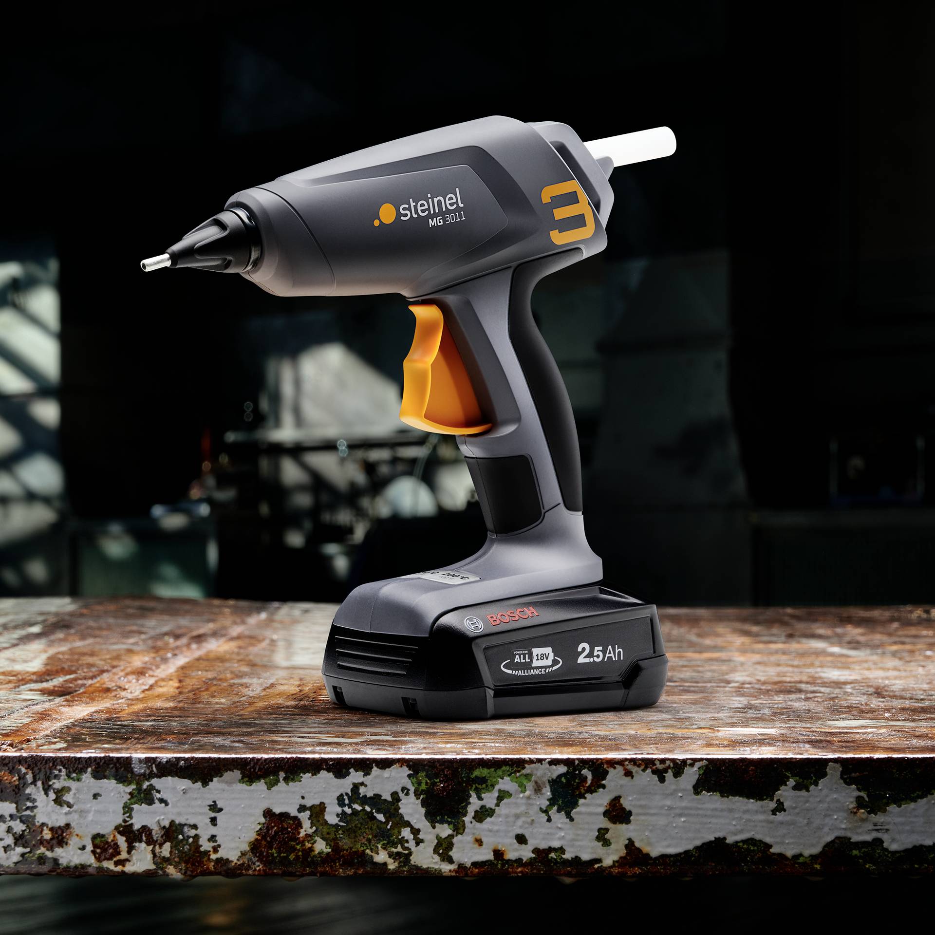 Klebepistole auf einem Tisch, bereit zur Verwendung. Die Pistole ist schwarz mit orangenen und grauen Details.