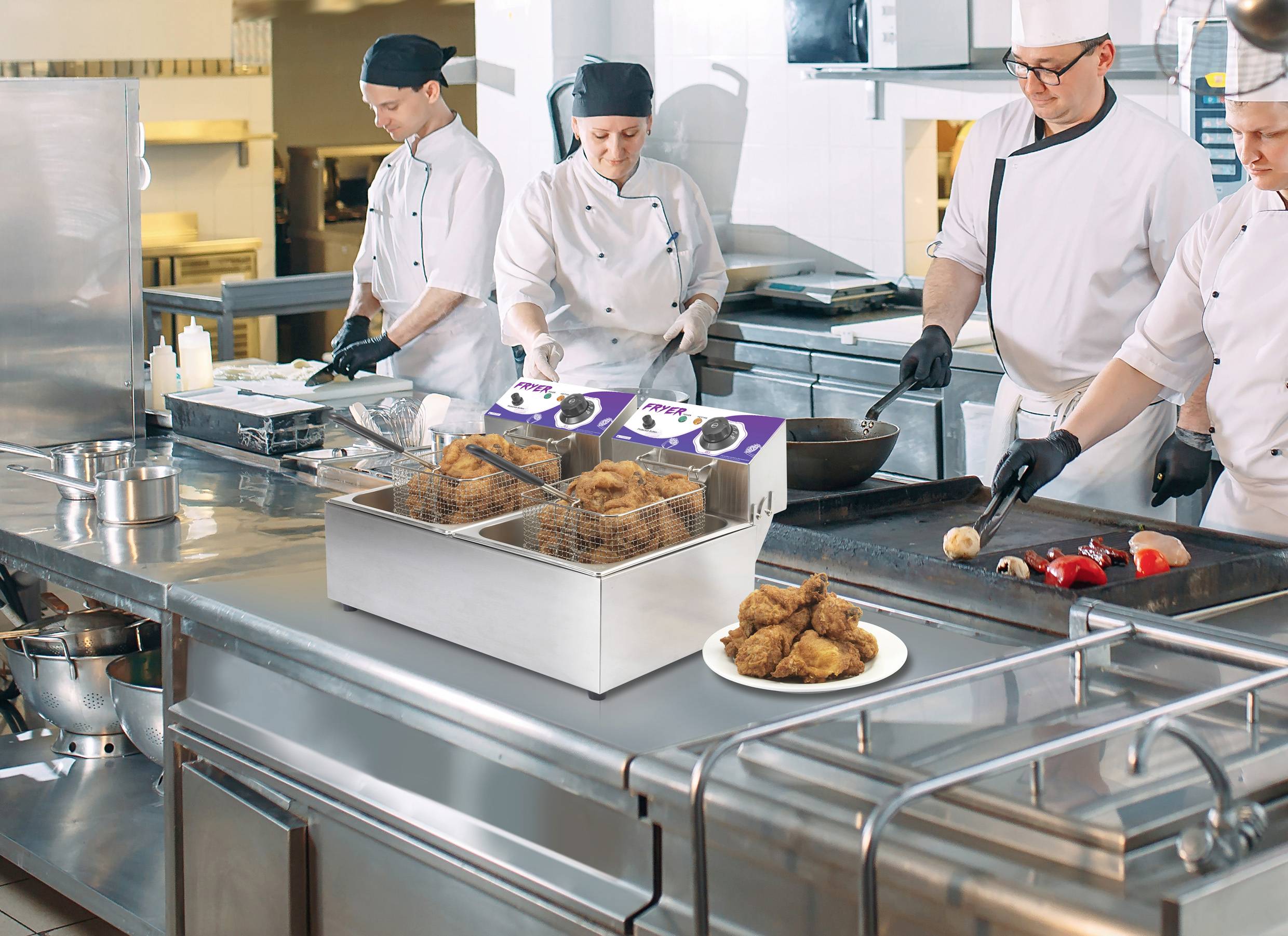 Köche in einer Großküche bereiten Essen zu. Im Vordergrund steht eine Fritteuse mit frittierten Speisen auf einem Teller.