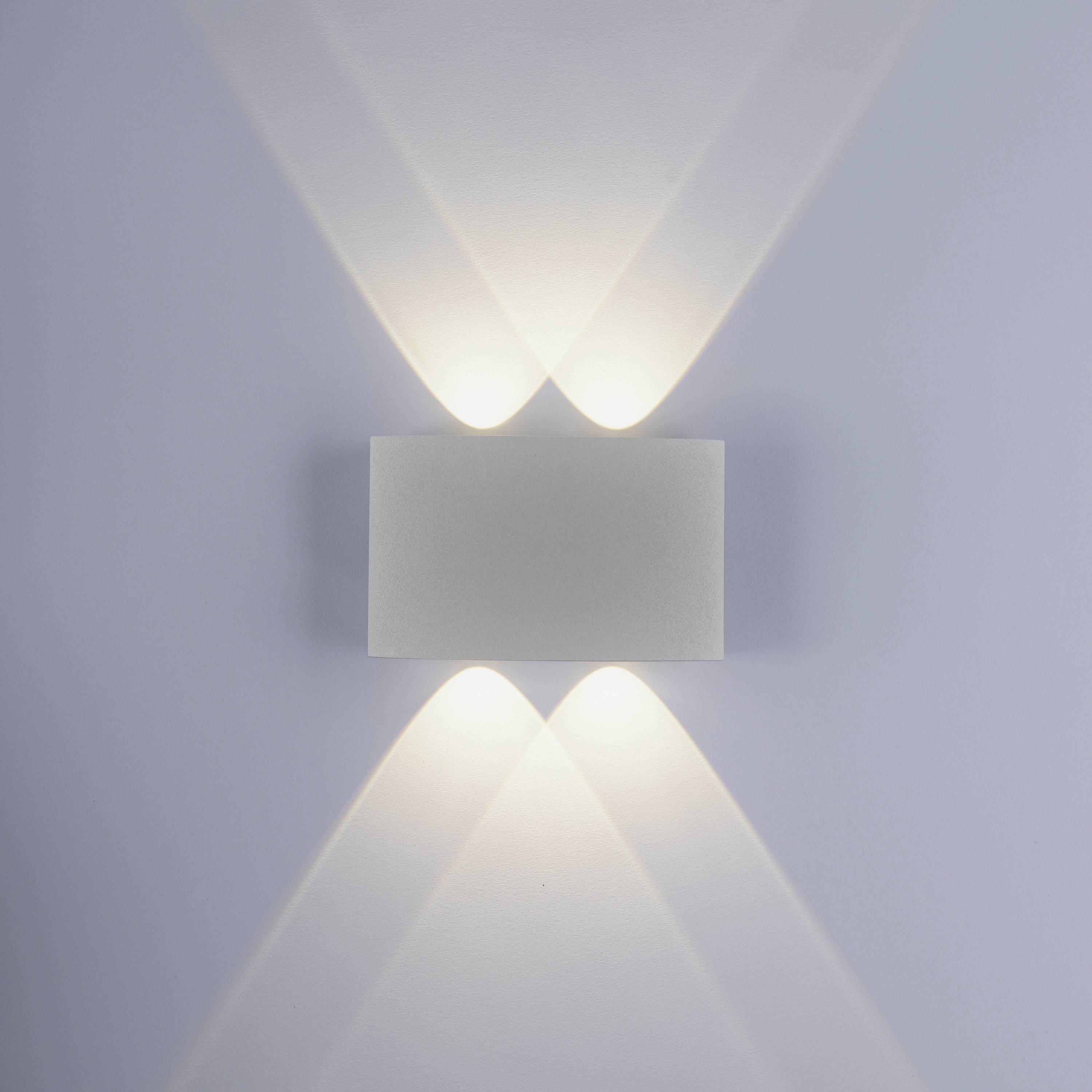Weiße Wandlampe mit modernem, geometrischem Design. Sie strahlt Licht nach oben und unten, wodurch ein stilvoller Lichtkegel entsteht.