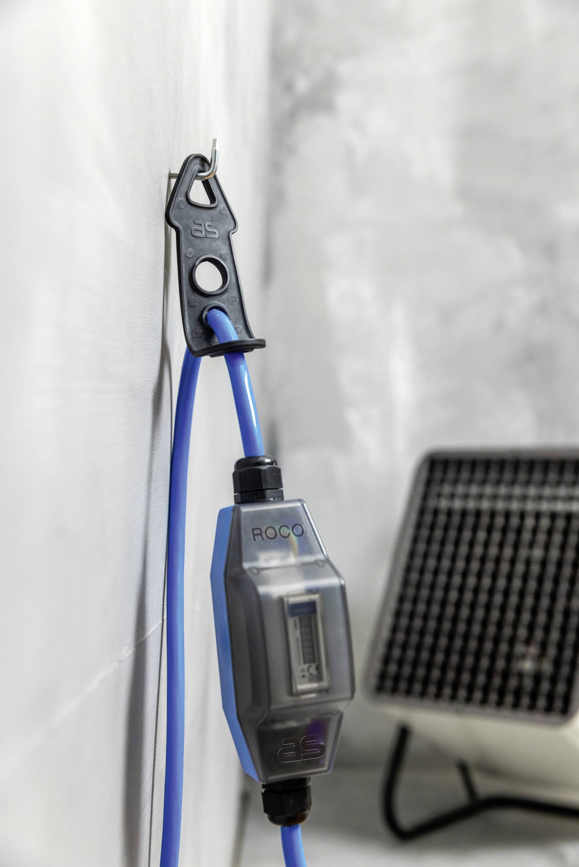 Ein blaues Ethernet-Kabel an der Wand mit einem Zähler, daneben ein elektrisches Heizgerät.