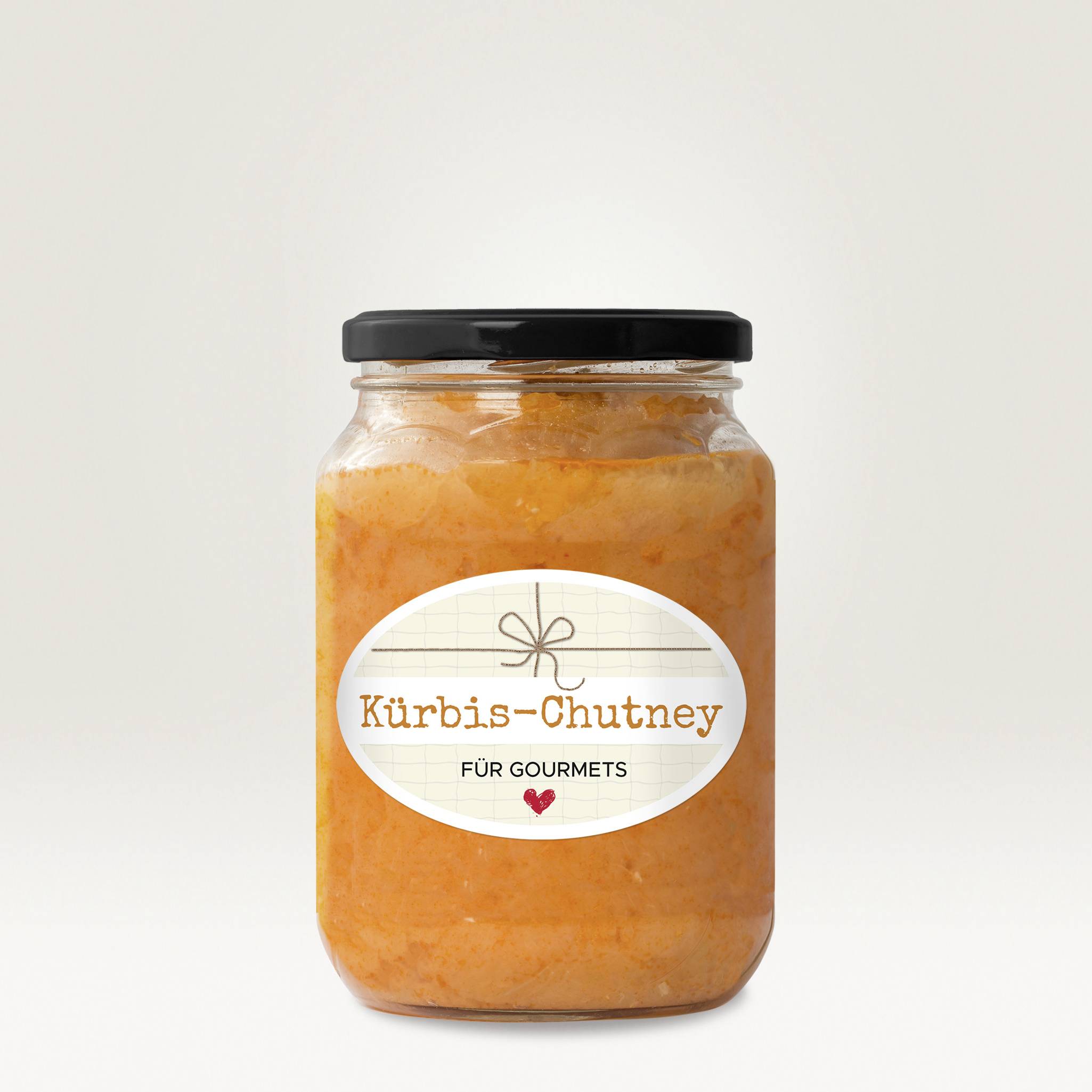 Ein Glas Kürbis-Chutney mit der Aufschrift 'Für Gourmets' auf dem Etikett, vor neutralem Hintergrund.