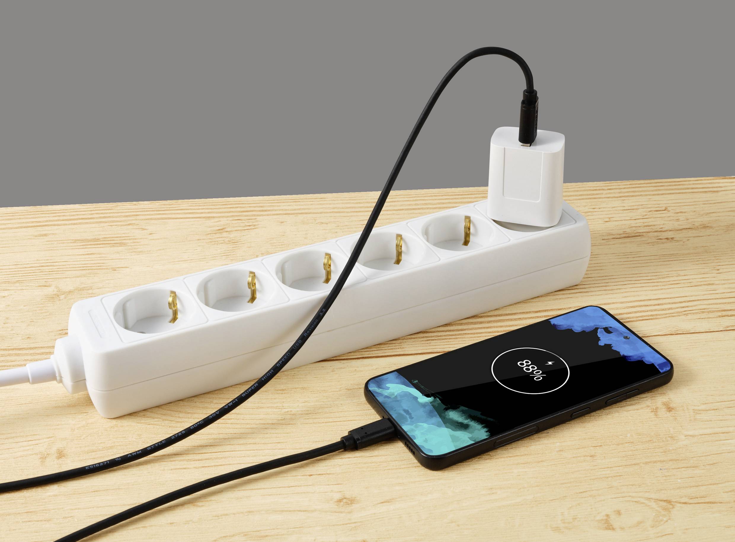 Ein Smartphone wird mit einem Kabel an eine Steckdosenleiste geladen. Die Batterieladung zeigt 80 % an.