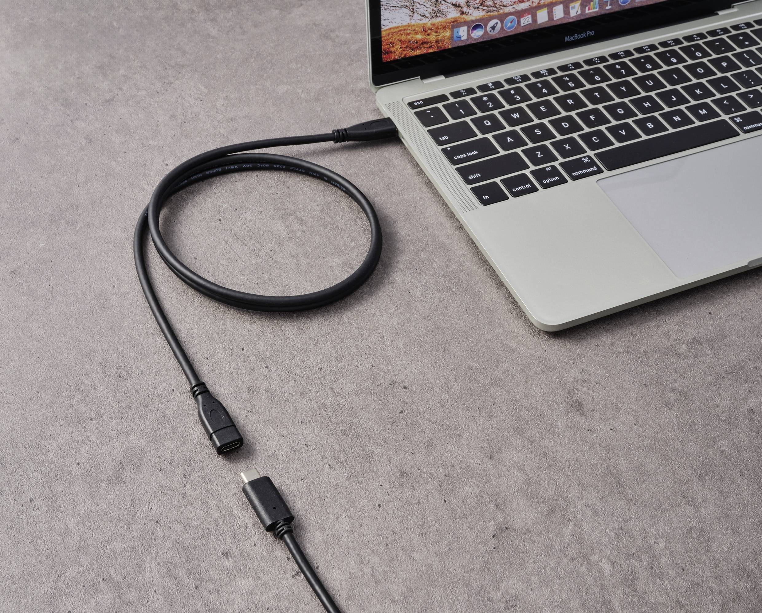 Ein Laptop steht auf einem Tisch, verbunden mit einem HDMI-Kabel, das daneben liegt. Es zeigt eine technische Einrichtungssituation.
