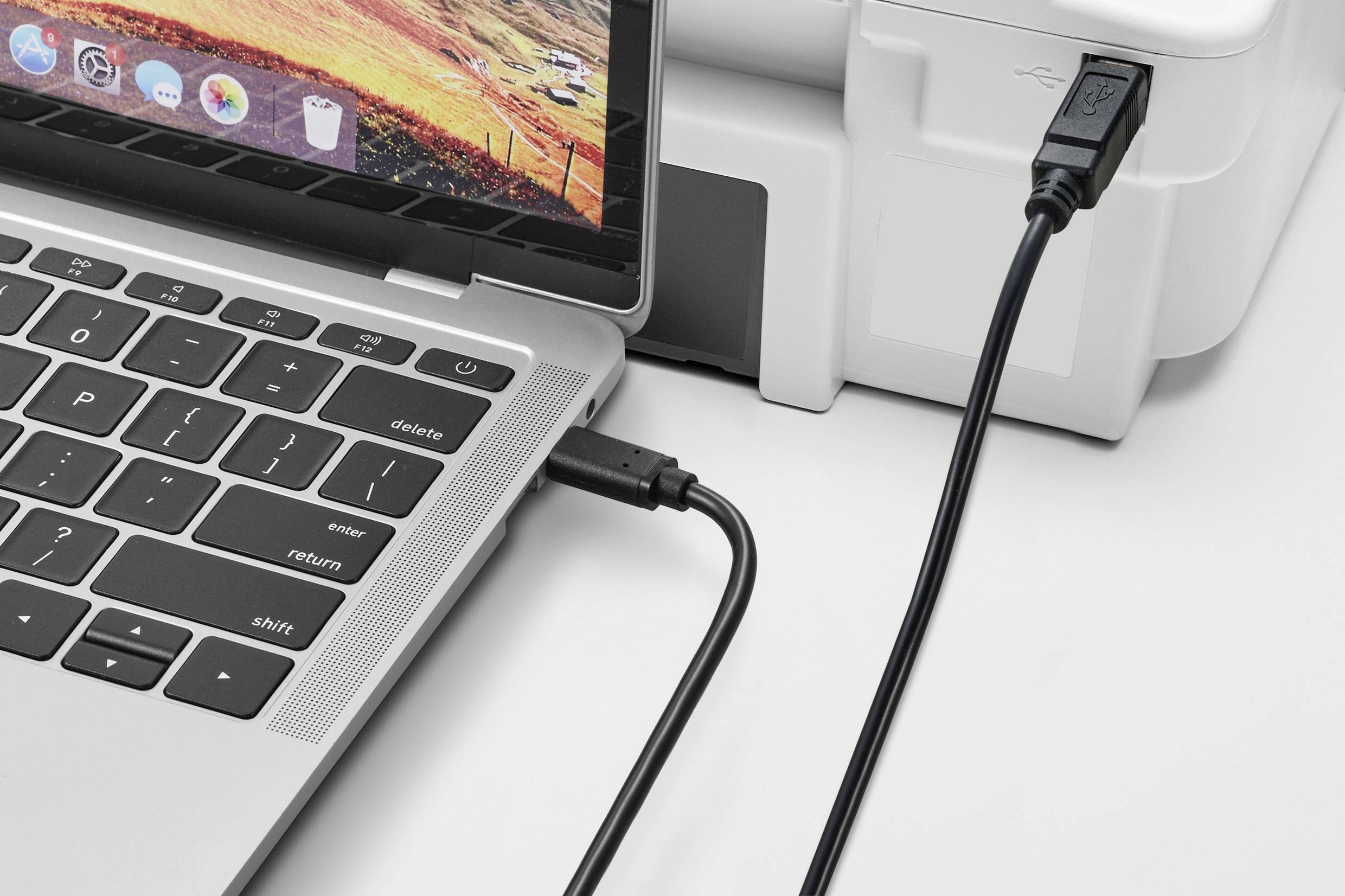 Ein Laptop ist über ein USB-Kabel mit einem Drucker verbunden, bereit zur Dateiübertragung oder zum Drucken von Dokumenten.