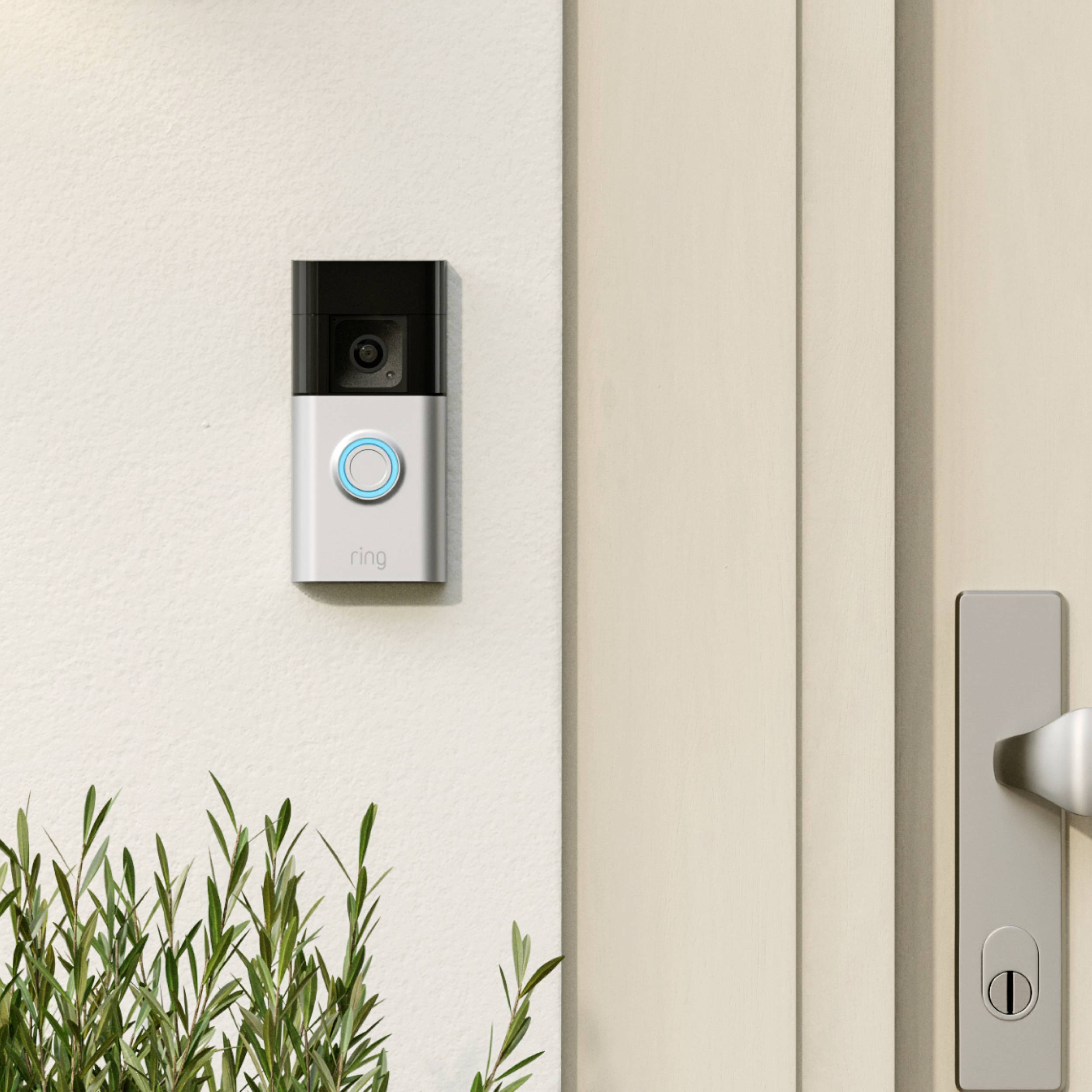 Eine smarte Türklingel mit Kamera und einem blauen LED-Ring ist neben einer Haustür installiert. Daneben ist ein Türgriff sichtbar.