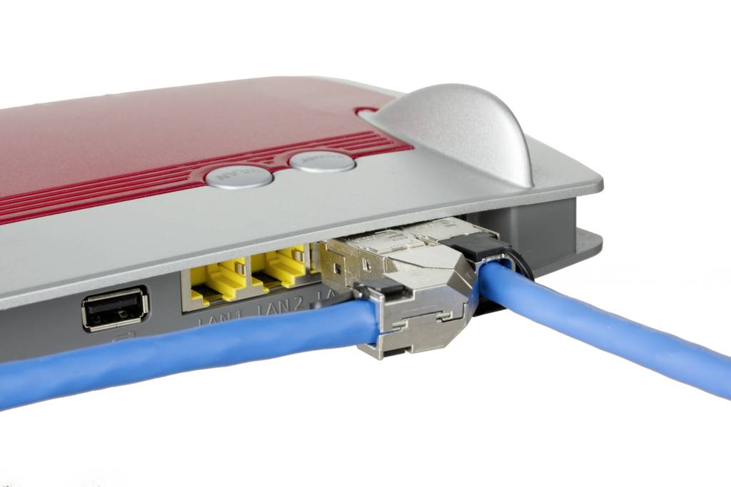 Ein roter WLAN-Router mit zwei blauen Netzwerkkabeln, die in die Anschlüsse an der Rückseite eingesteckt sind.