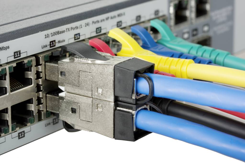 Nahaufnahme eines Netzwerkswitches mit mehreren eingesteckten Ethernet-Kabeln in verschiedenen Farben, die Netzwerkverbindungen darstellen.
