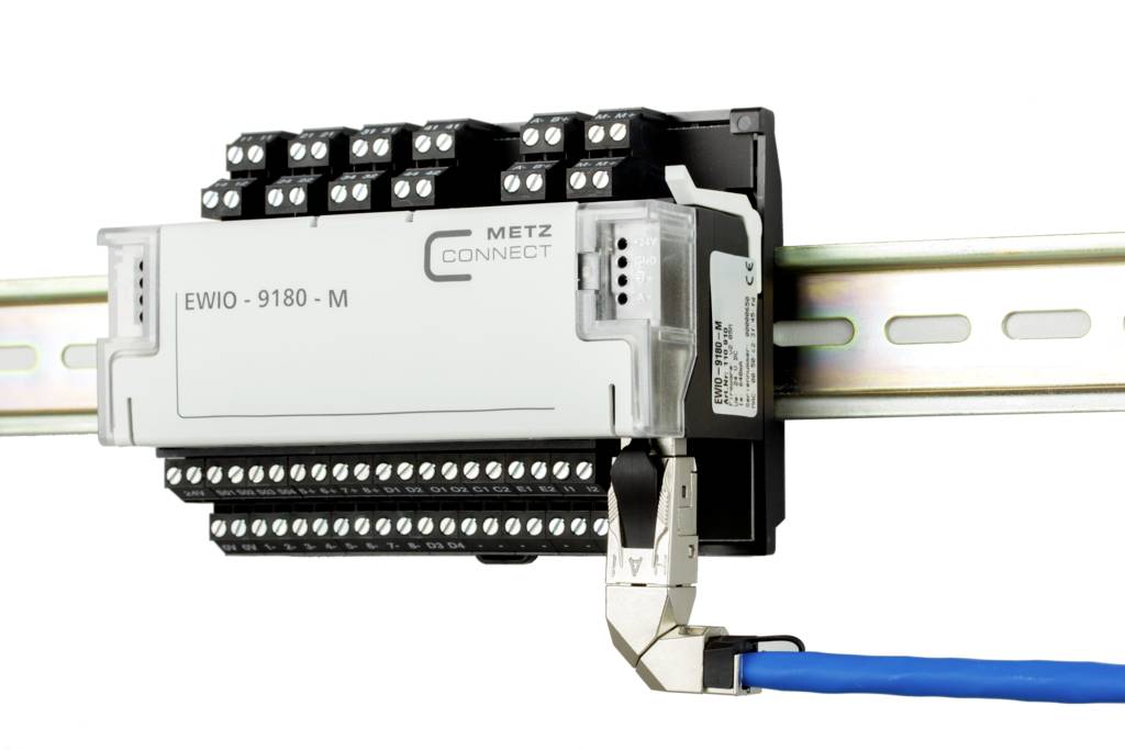 Ein Ethernet-Gerät ist auf einer DIN-Schiene montiert, verbunden mit einem blauen Kabel. Es hat mehrere Reihen von Anschlussklemmen.