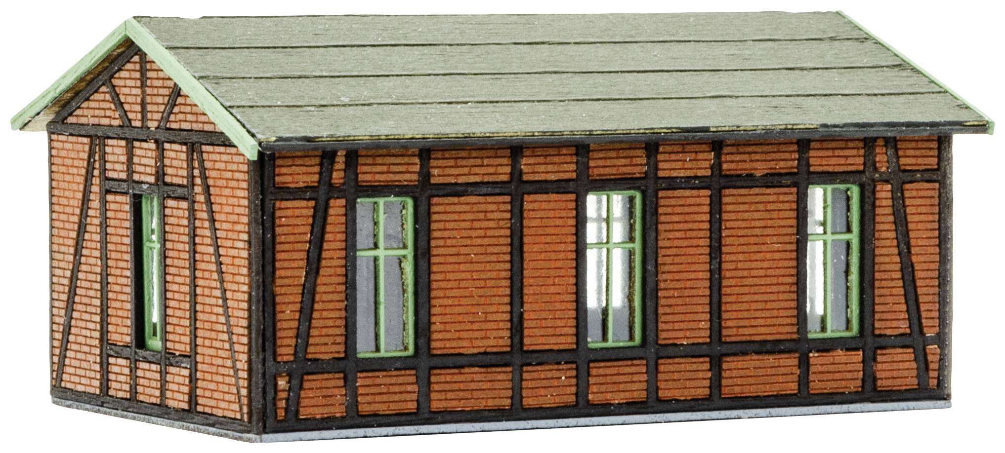 Ein kleines Modell eines Fachwerkhauses mit roten Ziegelwänden und einem grauen Dach. Drei Fenster sind auf der sichtbaren Seite.