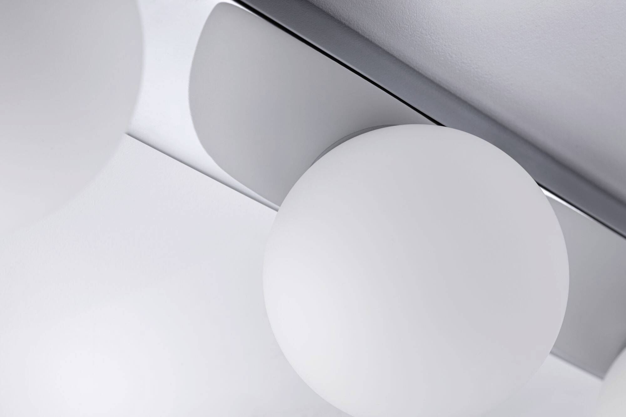 Weiße, kugelförmige Lampe an der Decke, nah aufgenommen. Modernes und minimalistisches Design mit glatter, silberner Halterung.