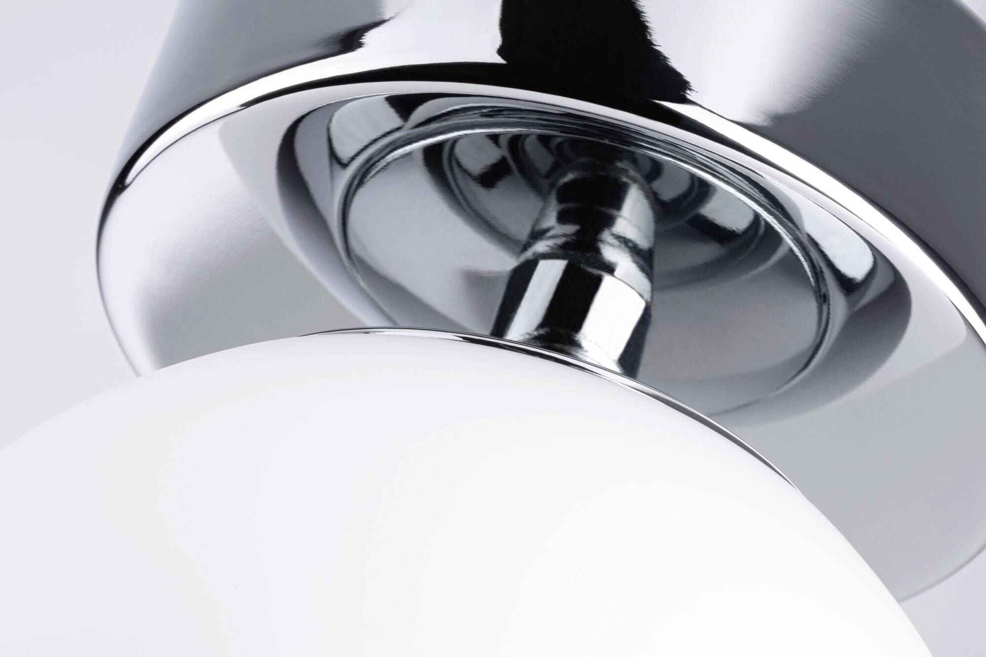 Eine Nahaufnahme einer modernen, chromfarbenen und weißen Tischlampe mit glatten Oberflächen.