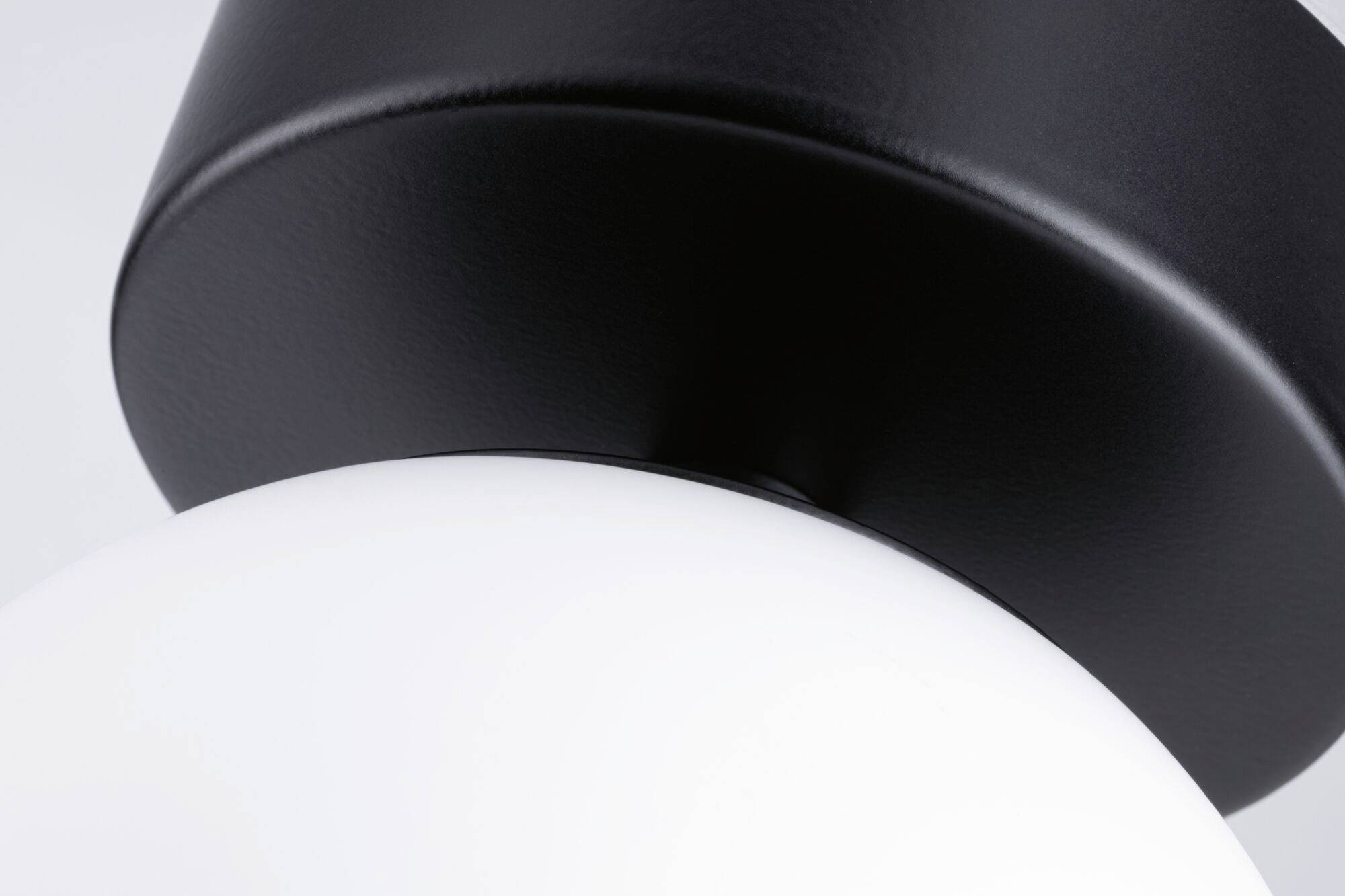 Nahaufnahme einer modernen Lampe mit schwarzem Metall und weißer Glaskuppel.