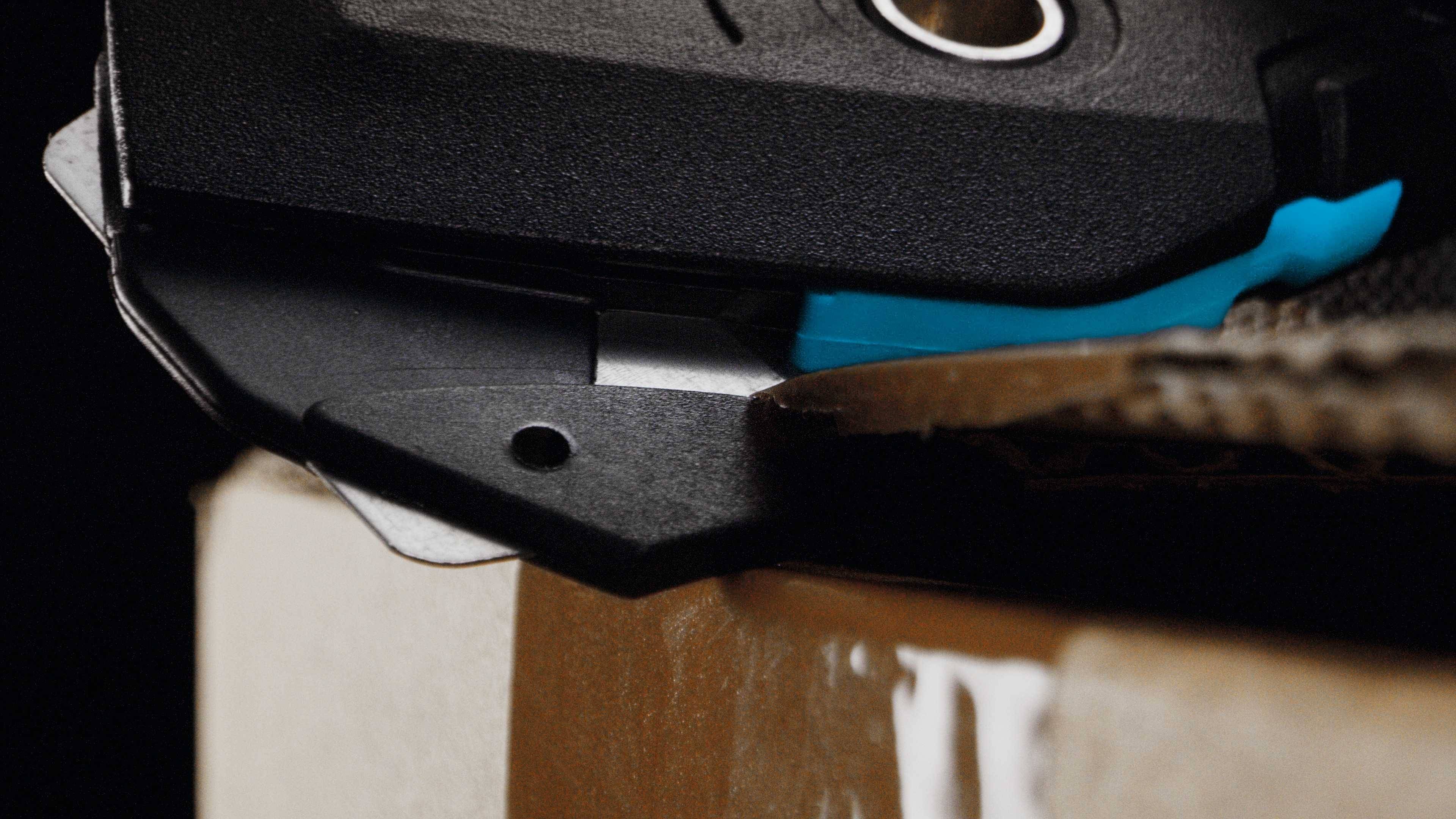 Ein Nahaufnahme zeigt ein scharfes Messer, das Pappe schneidet. Das Bild hebt die Genauigkeit und Schärfe des Werkzeugs hervor.