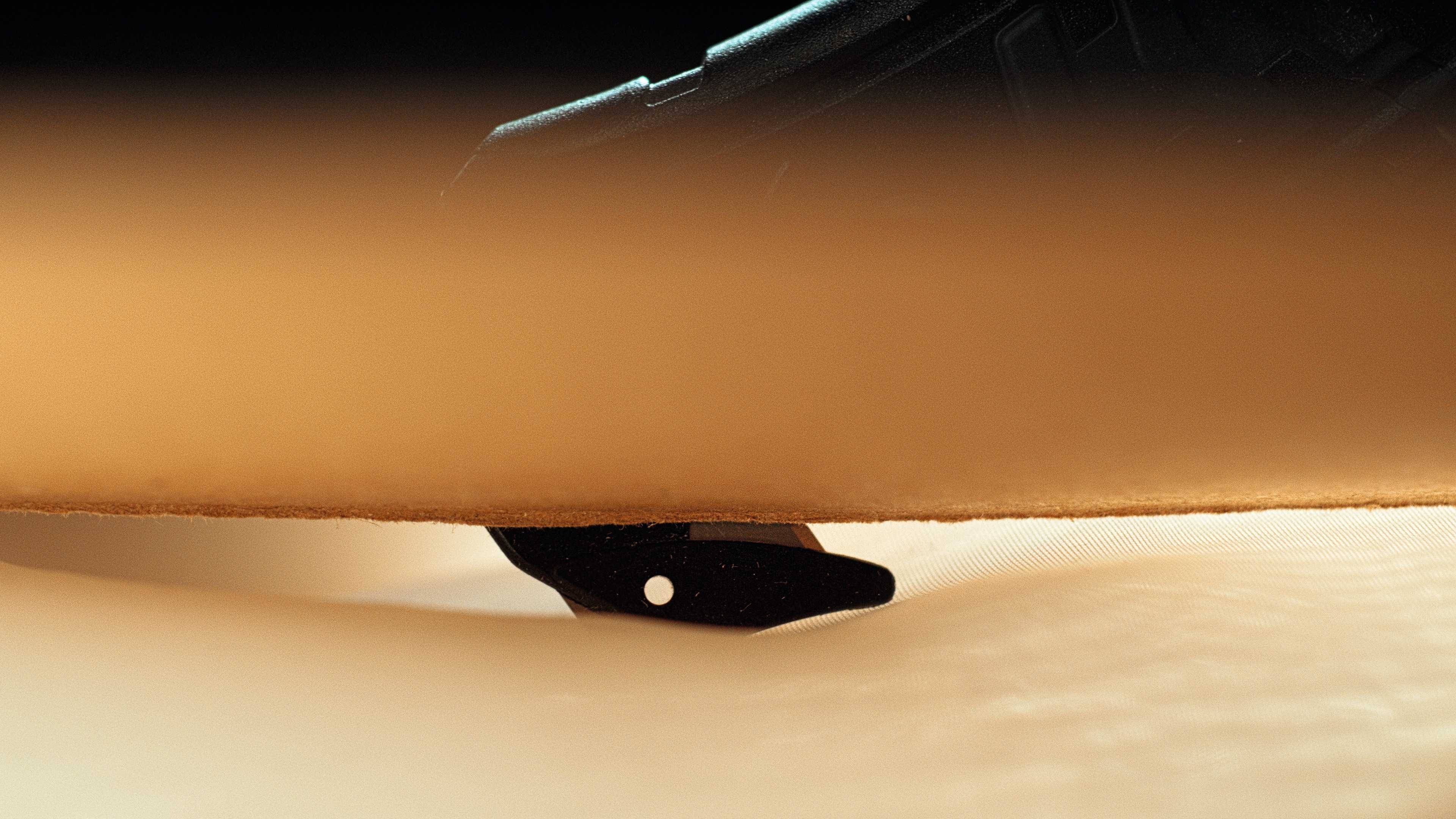 Ein Skateboard mit einem schwarzen Kicktail und einem Holzdeck auf hellem Bodenbelag, unscharfer Vordergrund im Bild.