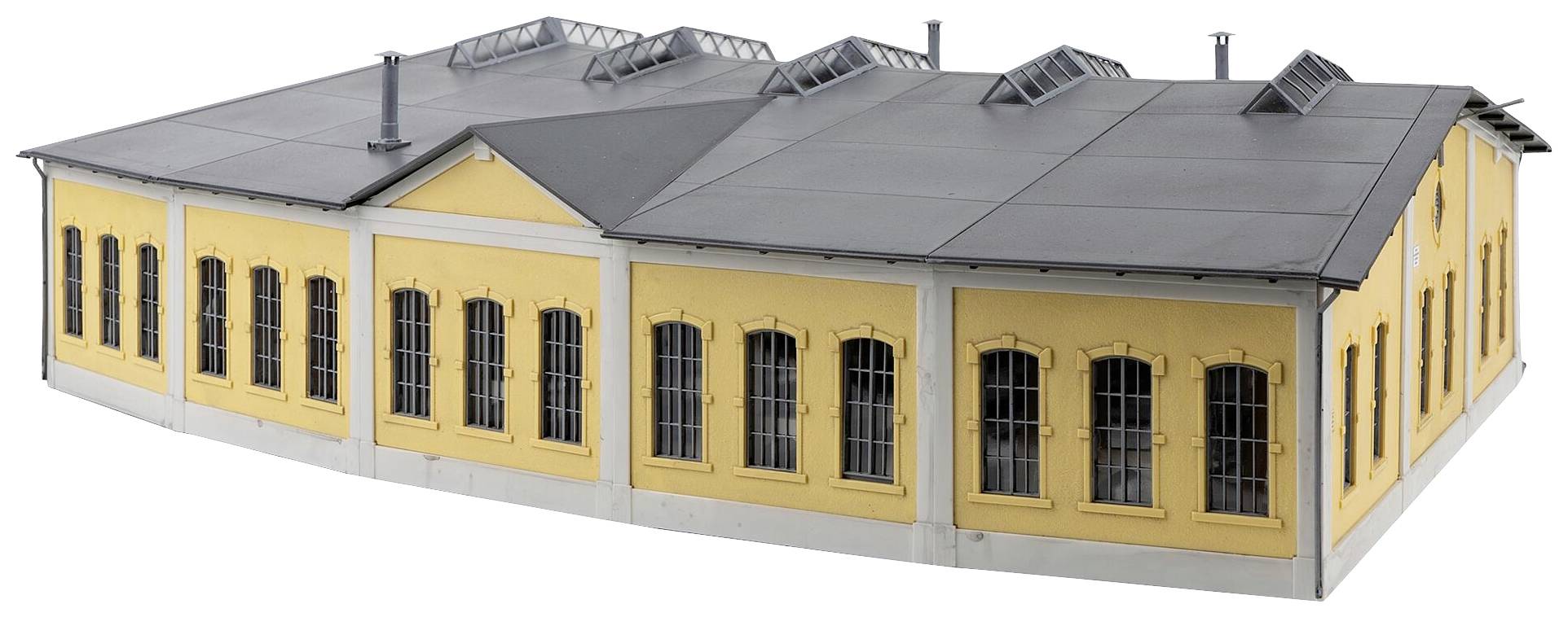 Gelbes Gebäude mit schwarzen Dächern und Fenstern in der Perspektive gesehen. Es scheint ein historisches Industriegebäude zu sein.