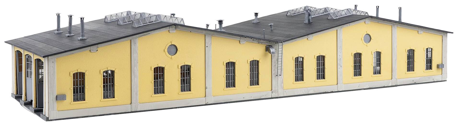 Gelbes Backsteingebäude mit grauen Dächern und mehreren Fenstern; Industriearchitektur mit Lüftungsrohren auf dem Dach.