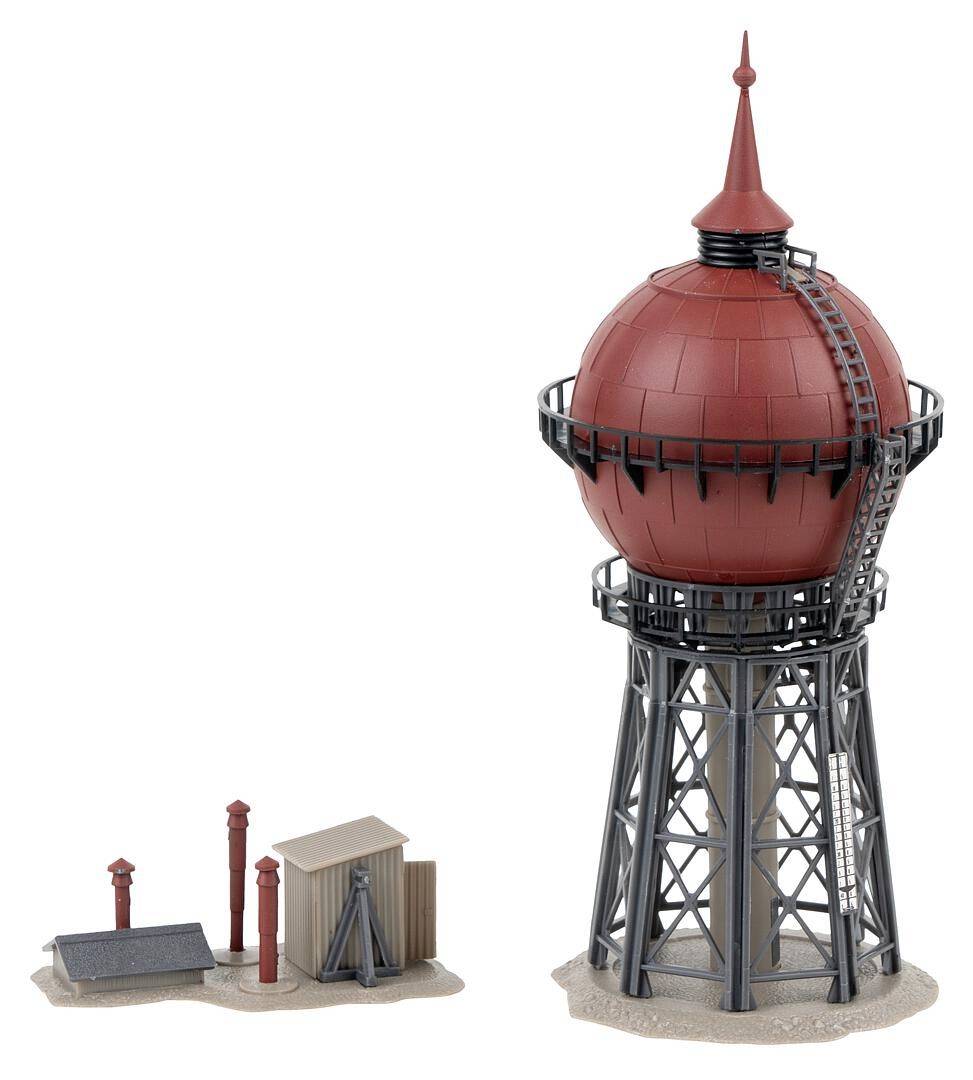 Ein roter kugelförmiger Wasserturm mit Metallgerüst und Leiter steht neben einem kleinen Gebäudeensemble mit Schornsteinen.